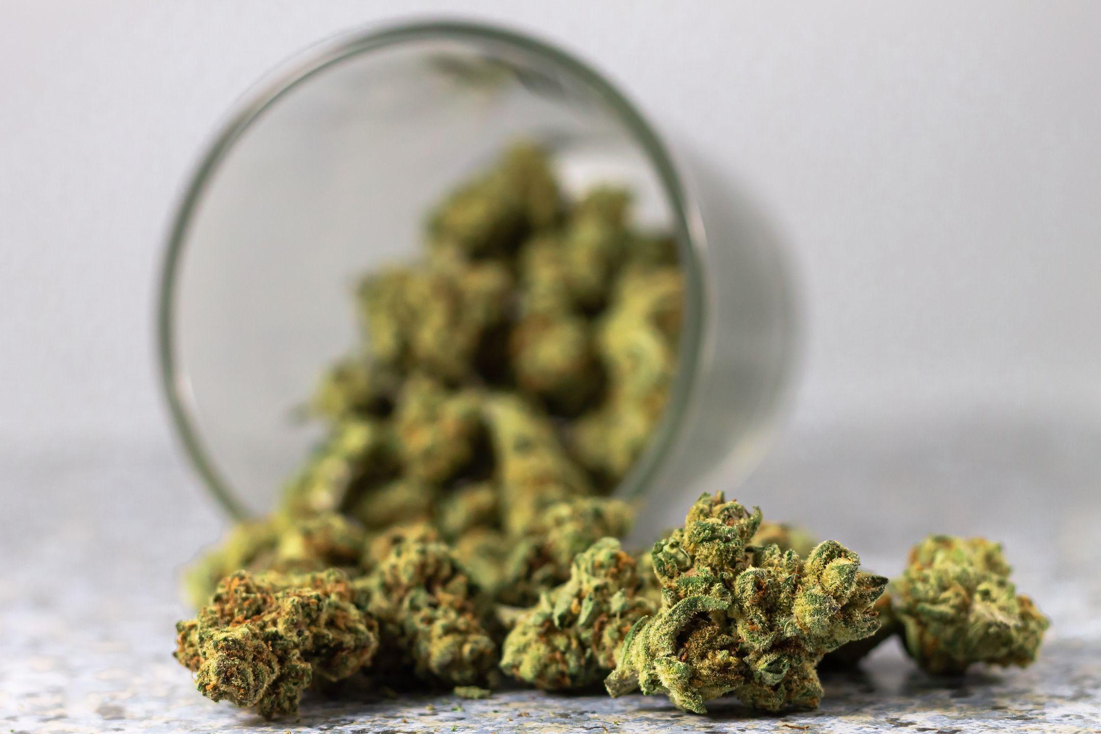 Detailed image of cannabis buds spilling from a glass jar, highlighting the green texture.