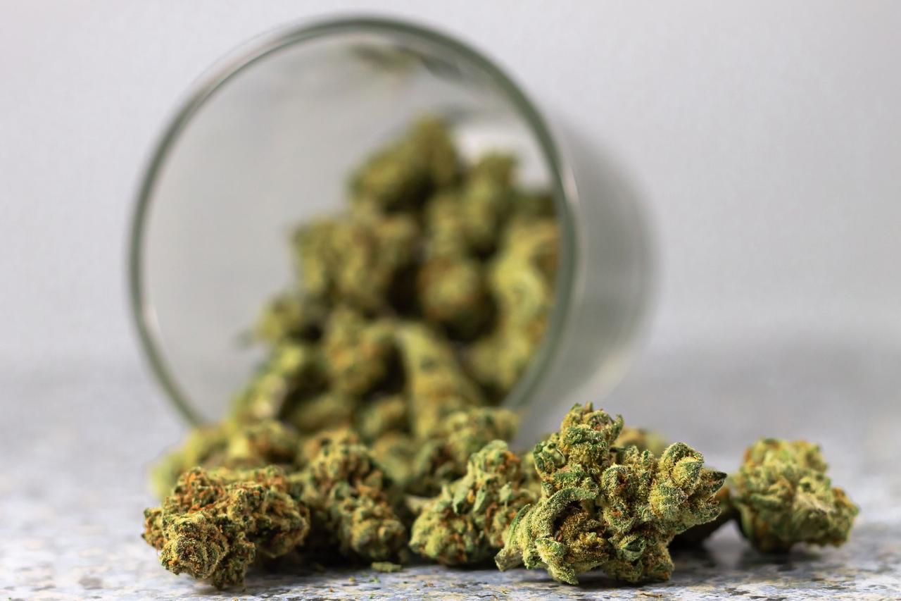 Detailed image of cannabis buds spilling from a glass jar, highlighting the green texture.