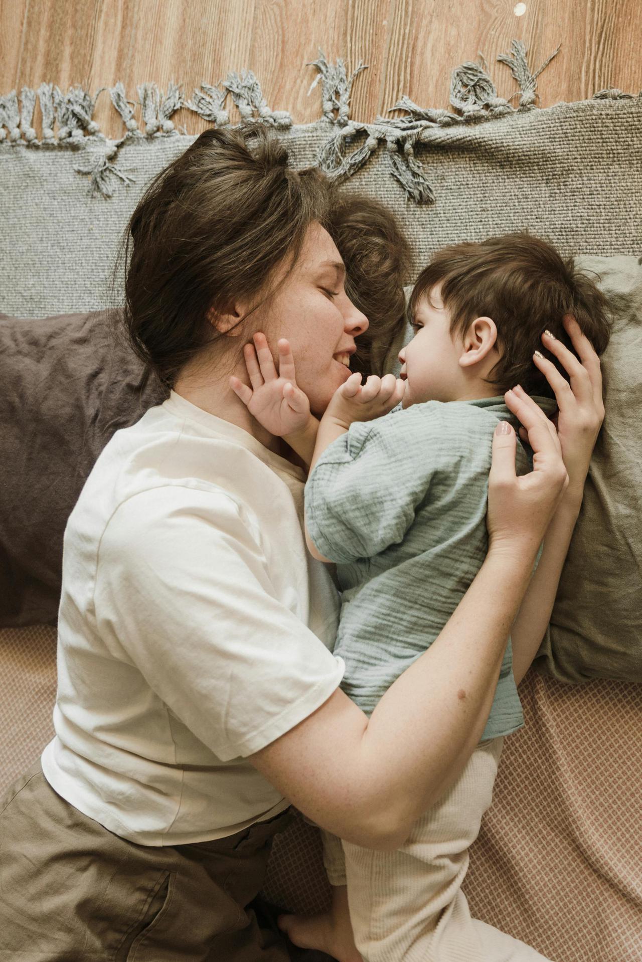 A tender moment shared between a mother and child relaxing on a bed, showing love and care.