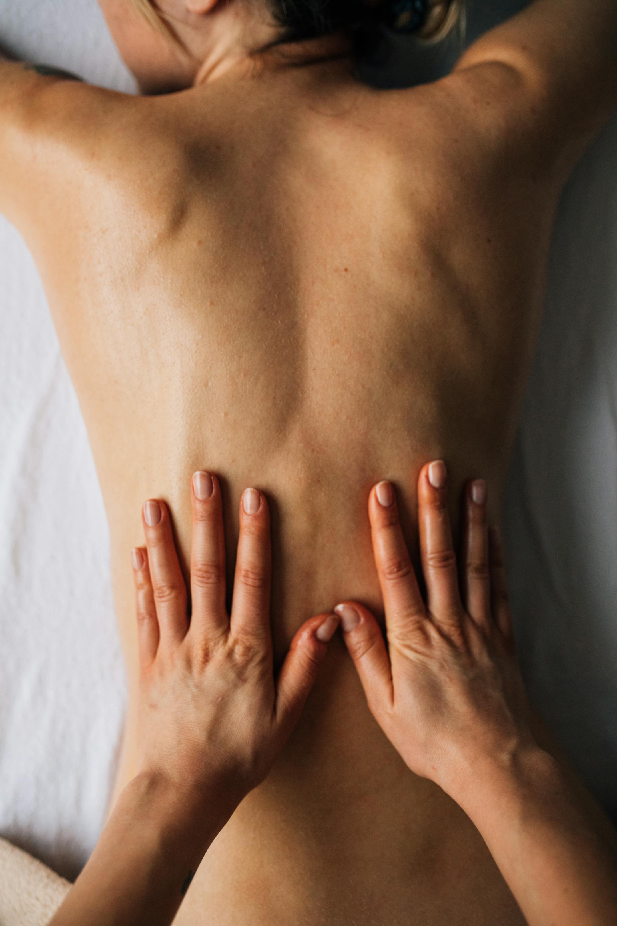 Hands massaging a person's back for relaxation in a calming indoor setting.