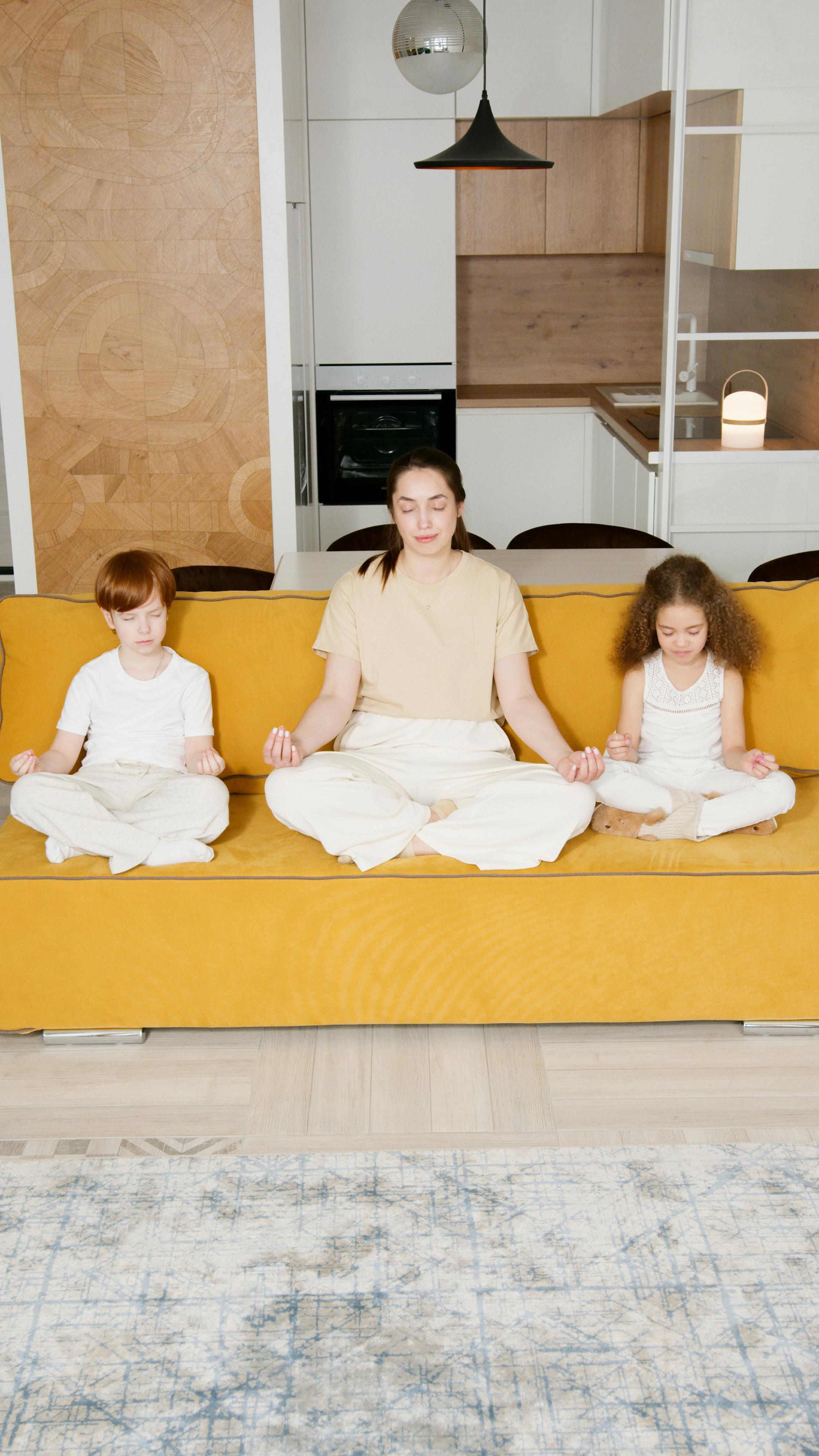 Mother and children meditating in living room, promoting family bonding and wellness.