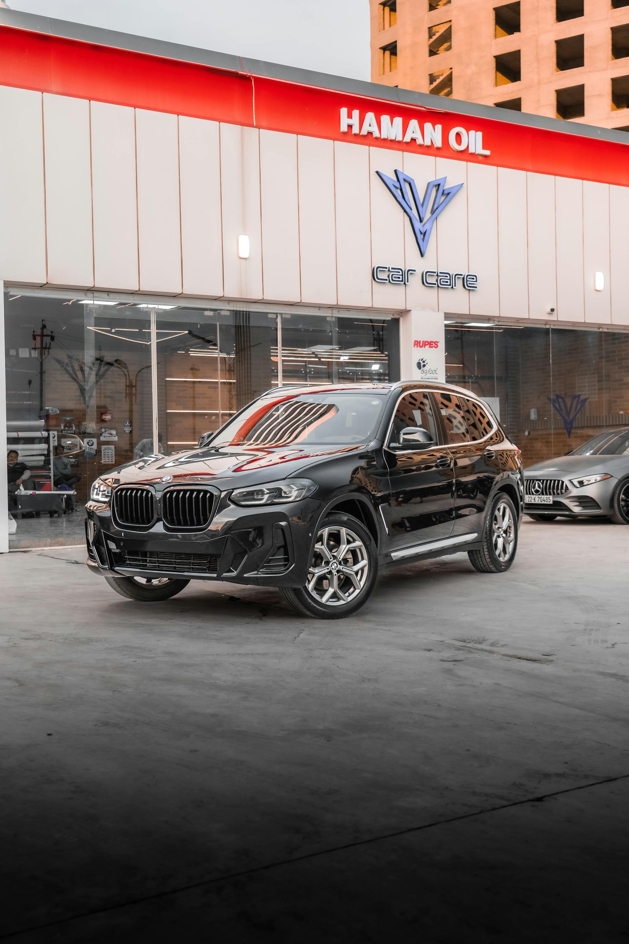 Black BMW X3 SUV parked at a professional car care center, reflecting sleek design and luxury.
