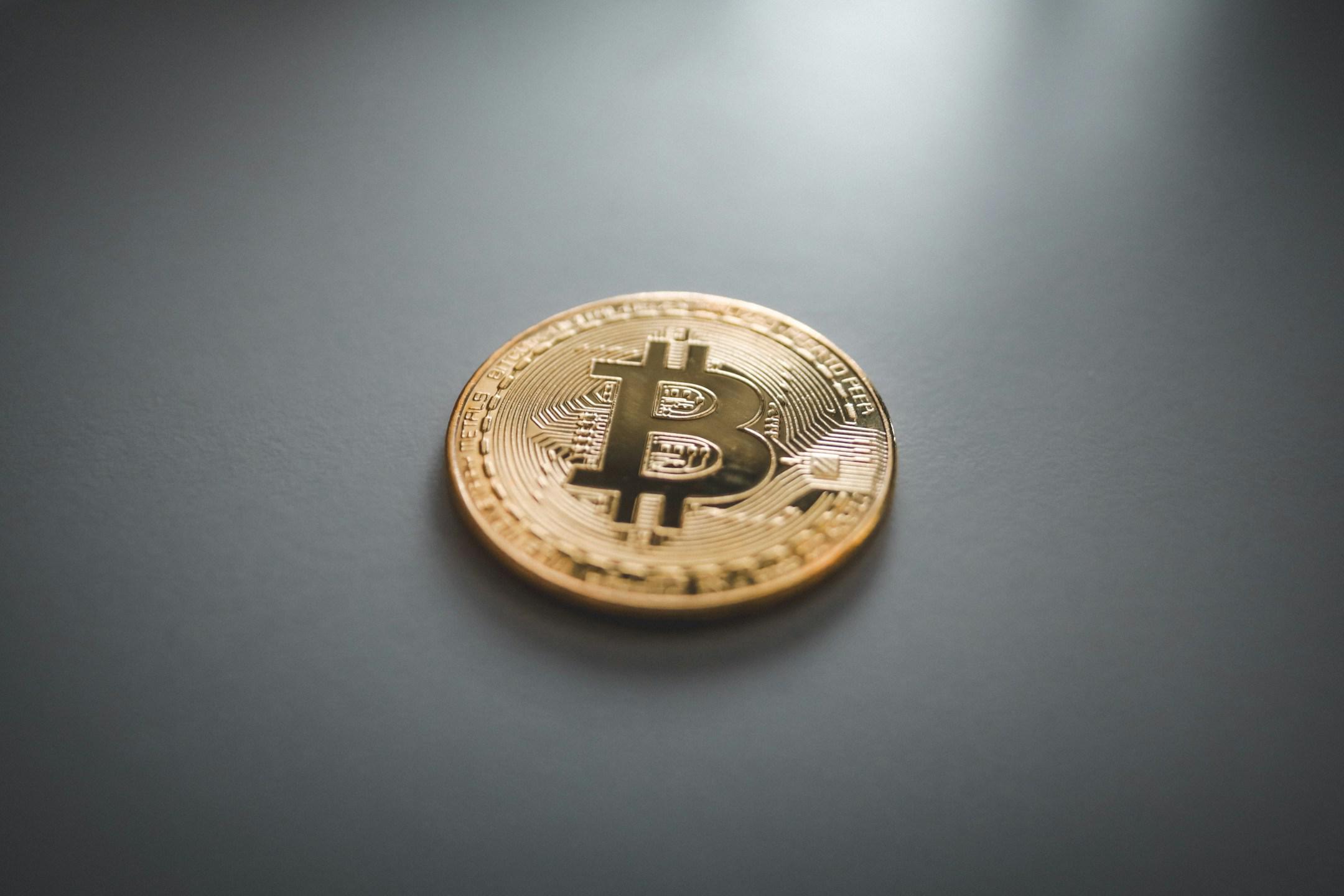Physical Bitcoin (BTC) coin on white surface.