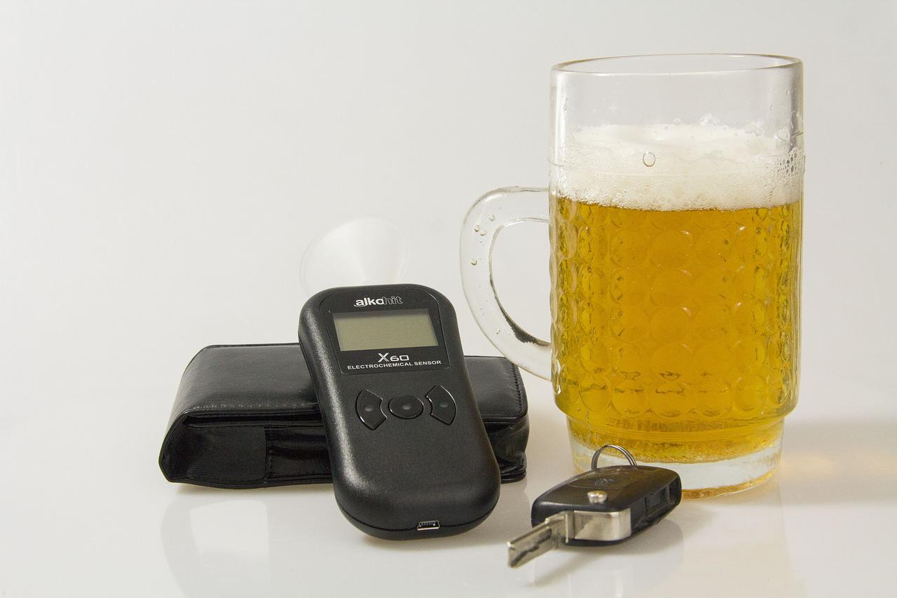 A beer beside keys and a breathalyzer.