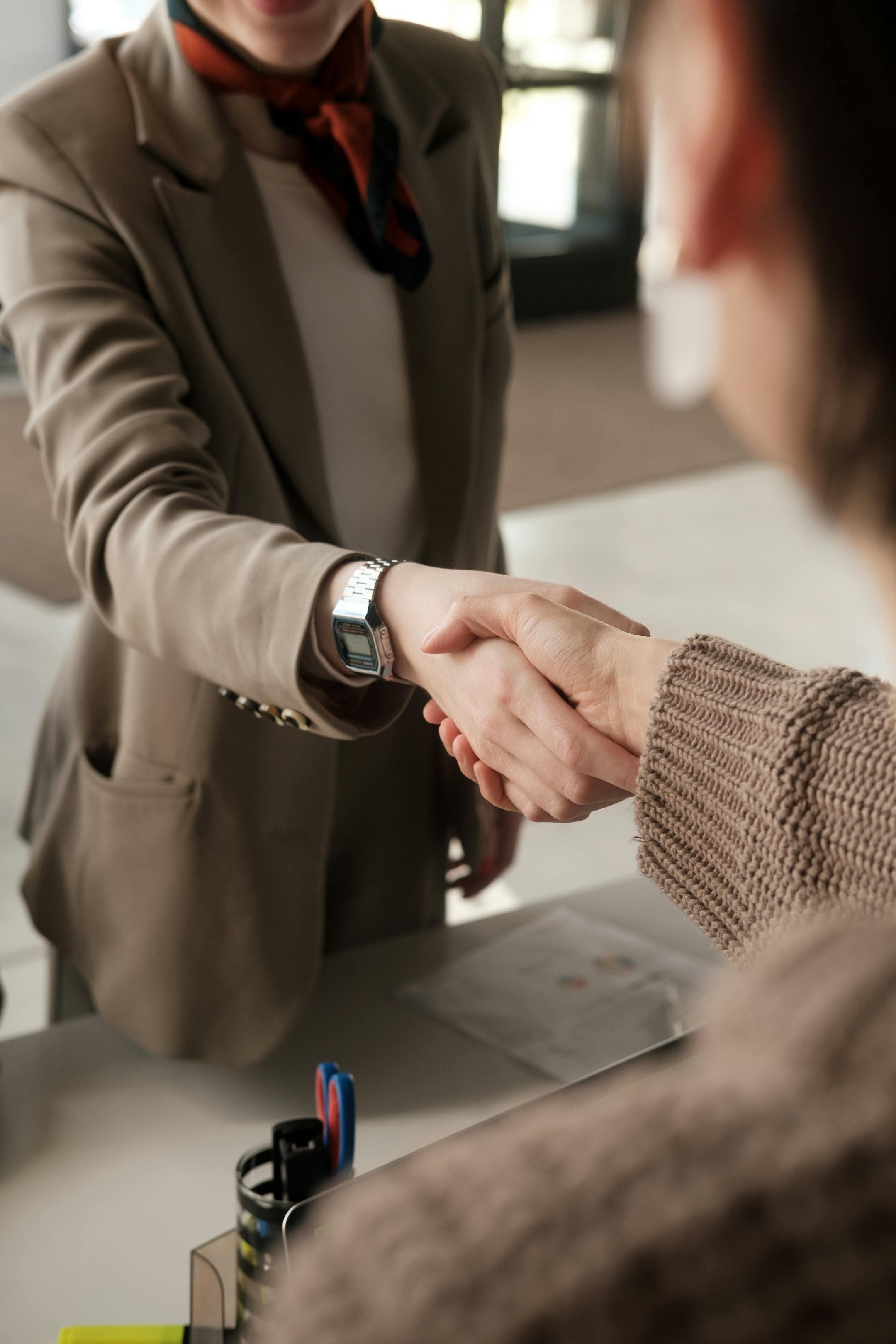 Two professionals shaking hands in an office, signifying a successful business agreement.