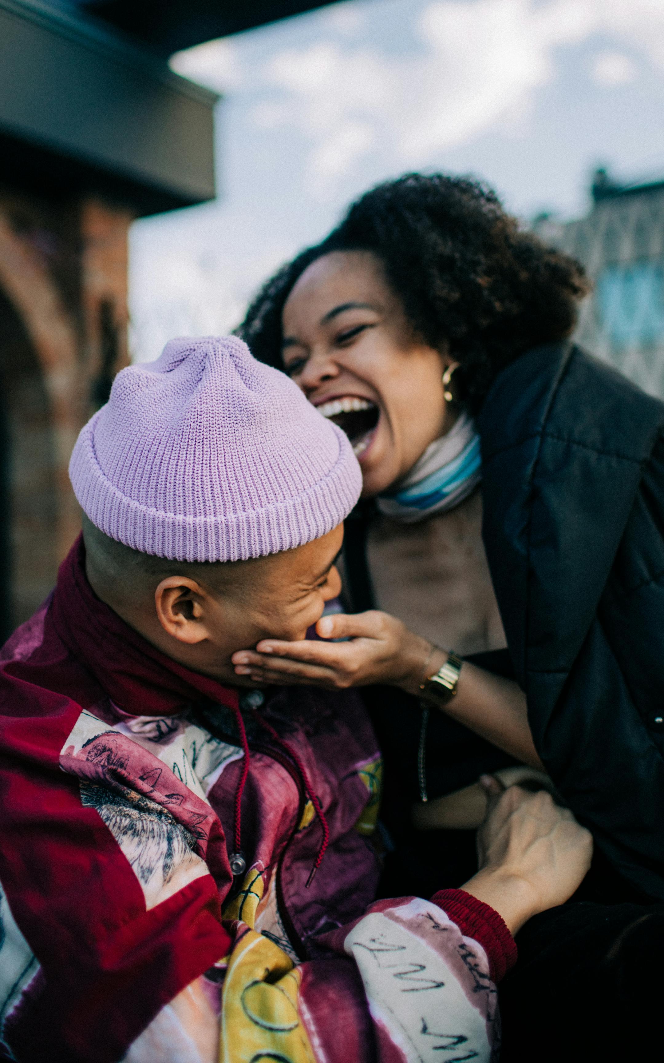 Warm, authentic moment of a couple laughing together outdoors, capturing happiness and connection.