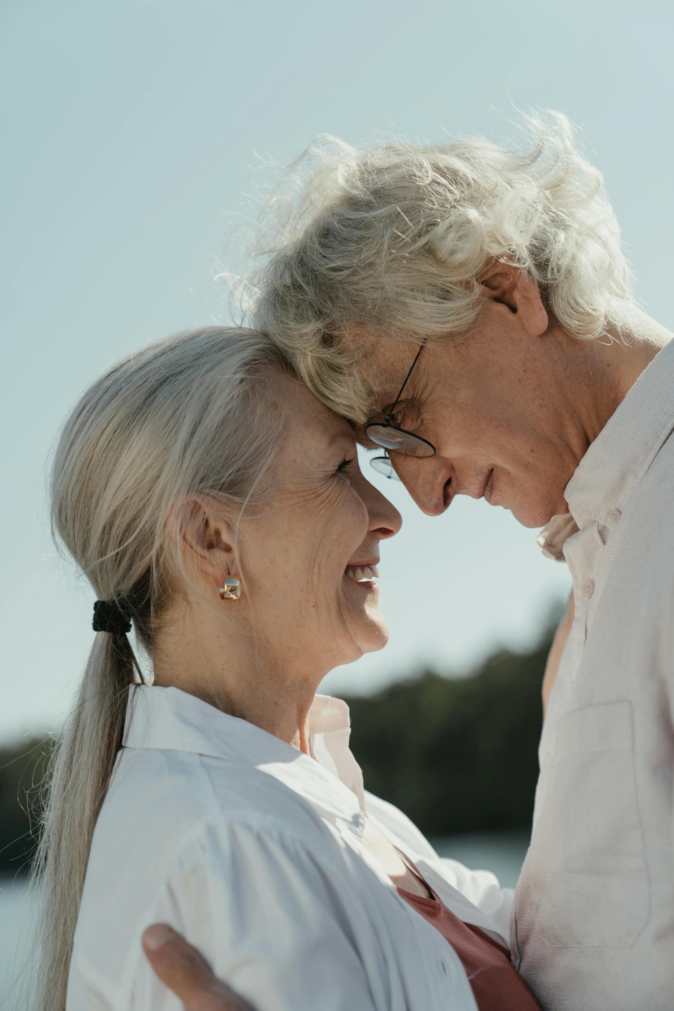Senior couple sharing a loving moment outdoors with a warm embrace.