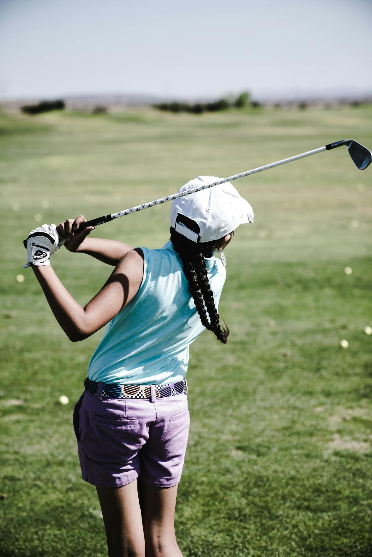 Girl practicing golf swing on a sunny day at the golf course