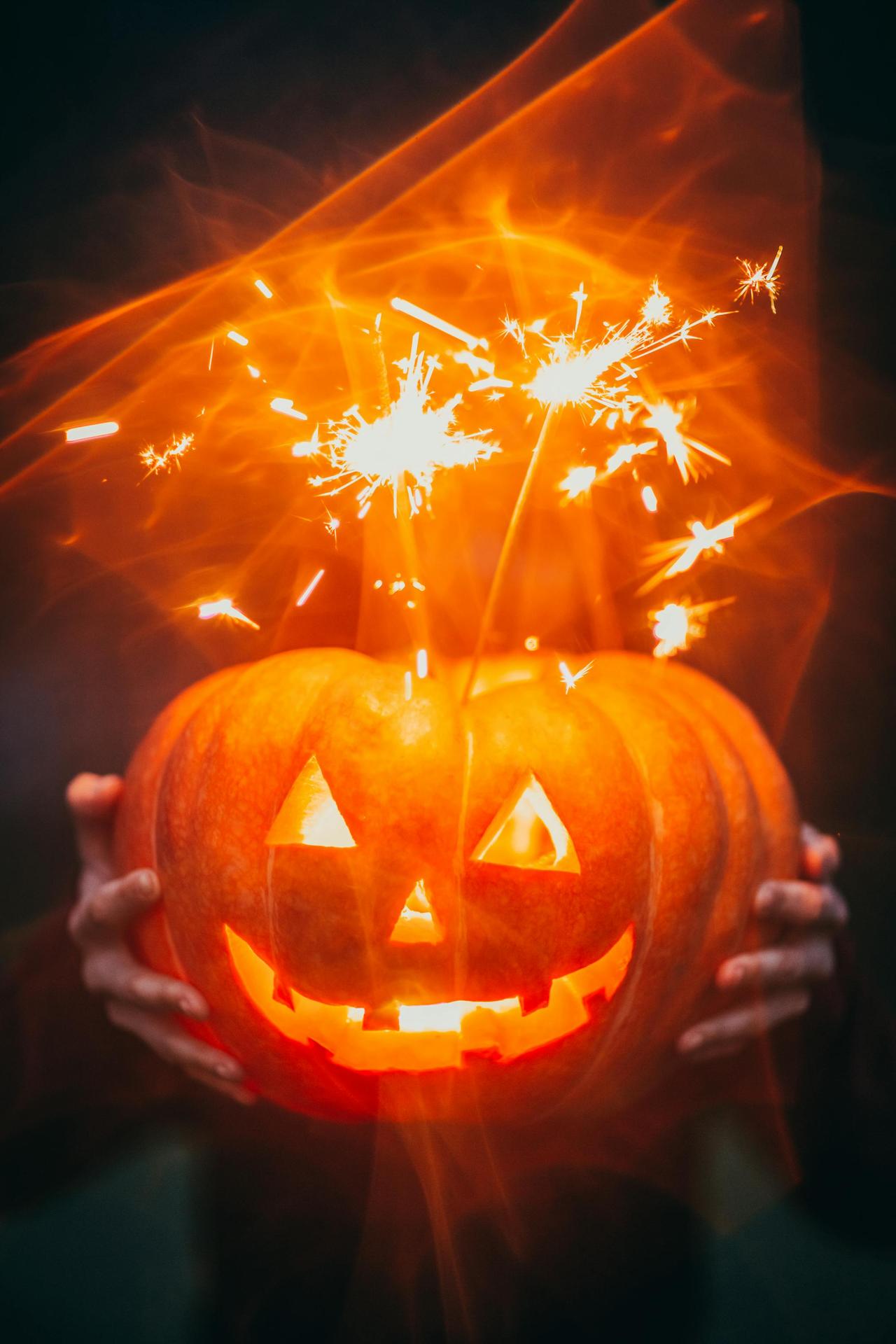 Glowing Halloween pumpkin with sparklers creating an eerie effect.