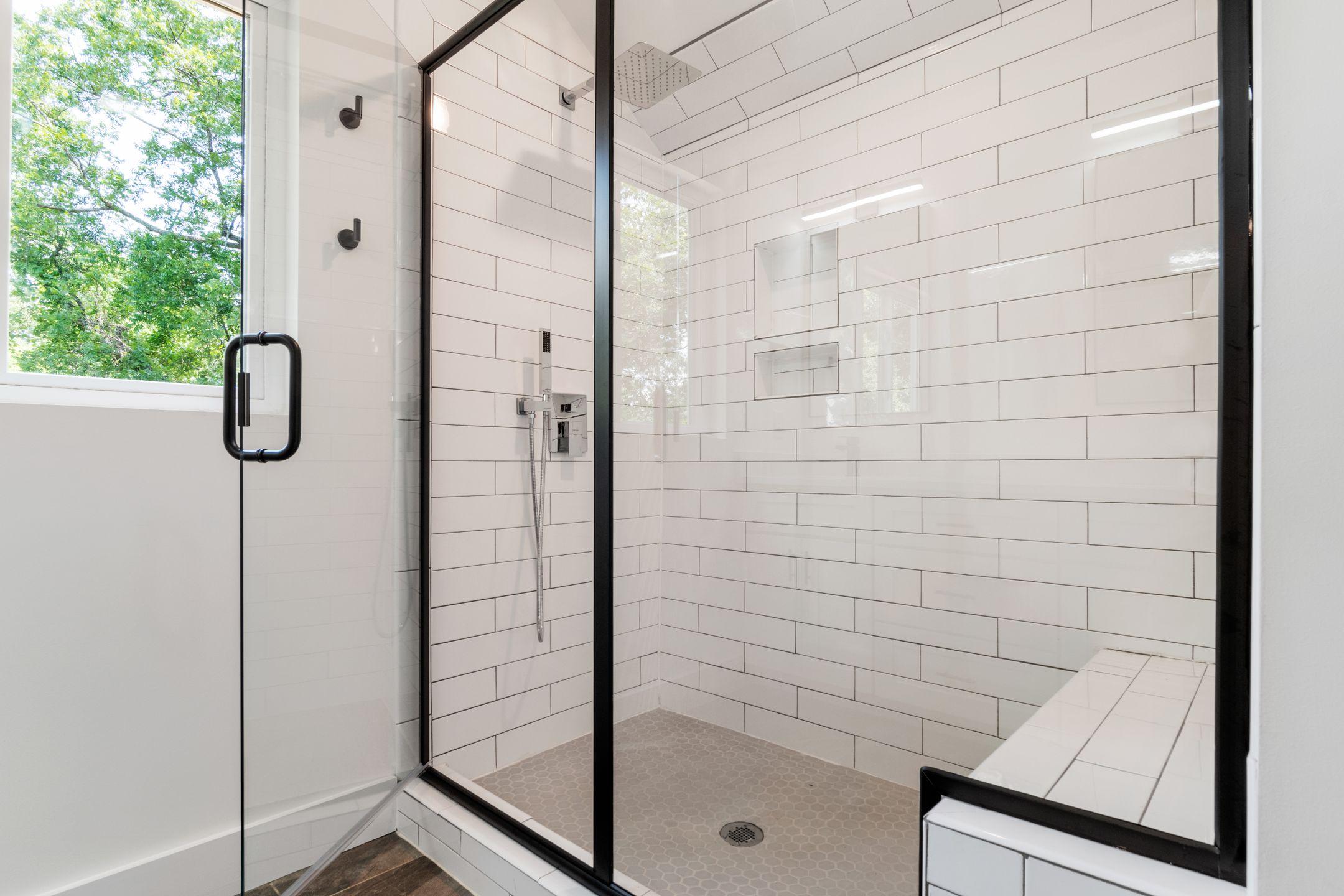 Sleek and modern shower with glass panels and tiled walls in a bright bathroom.
