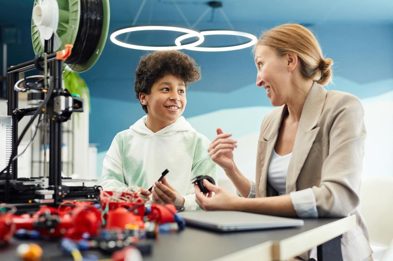 Child and adult engaged in STEM activity with 3D printer indoors.