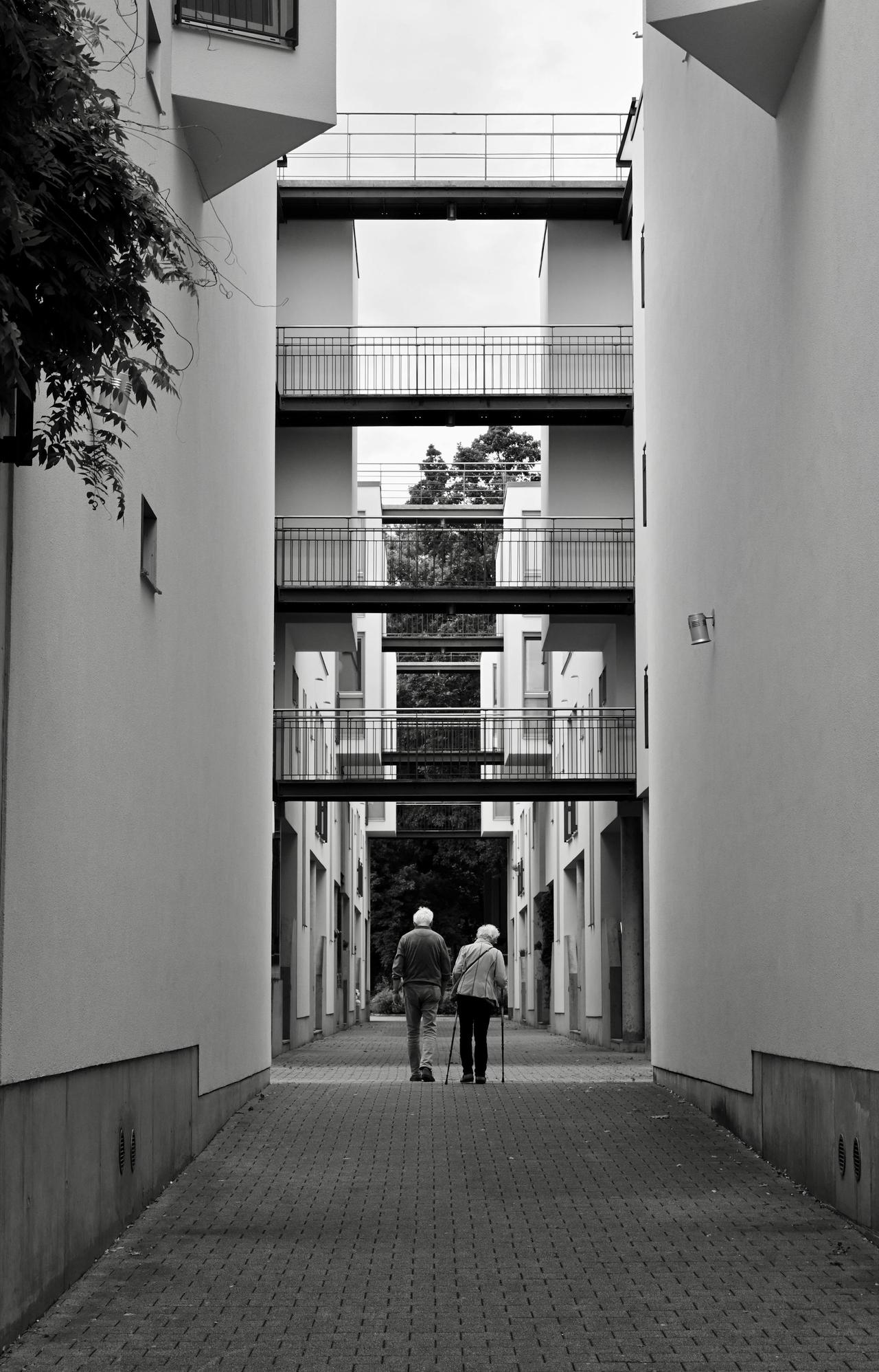 Black and white photo of a senior couple walking through modern buildings in Hamburg.