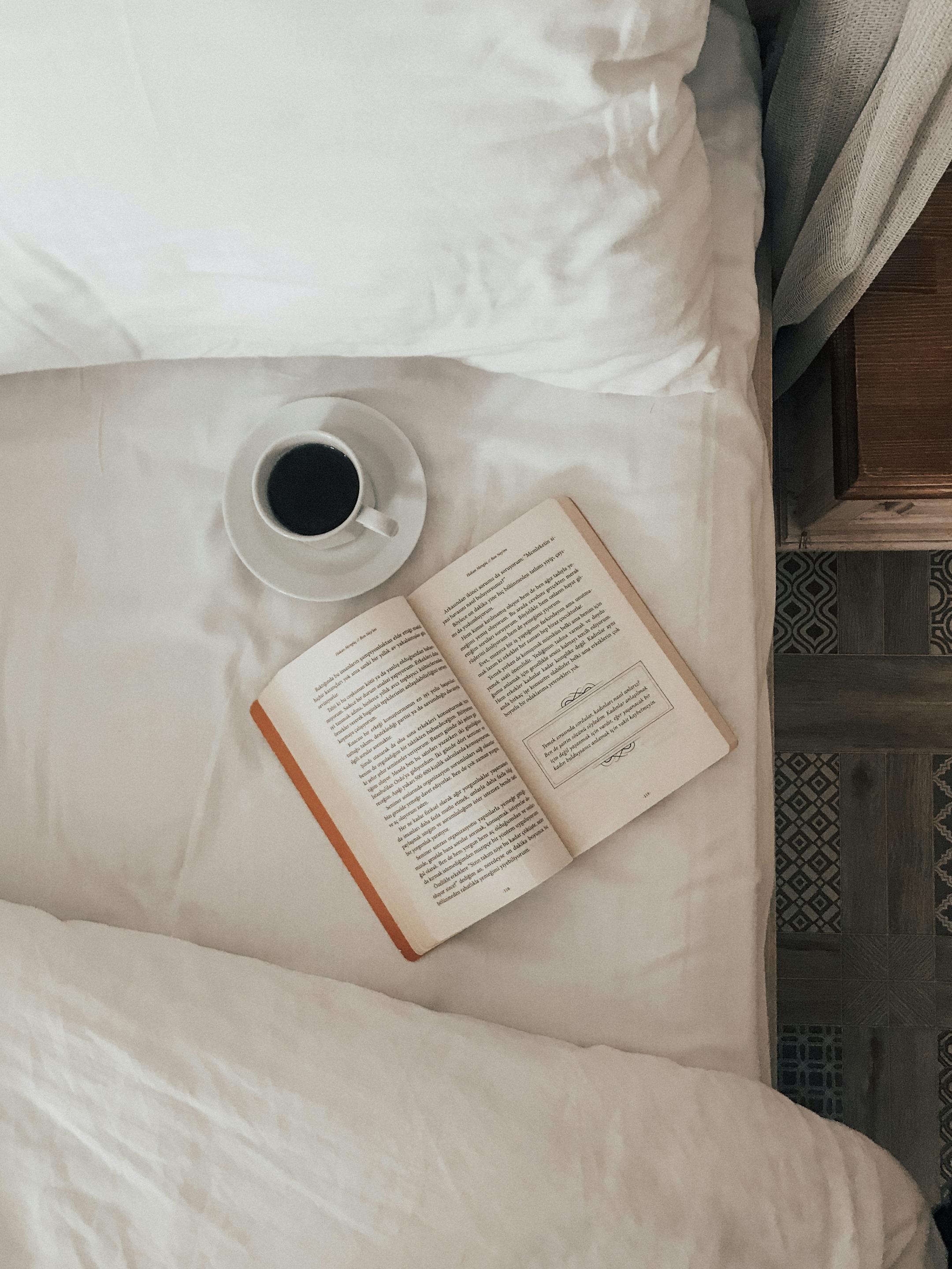 A calming indoor scene with a book and coffee on the bed, perfect for relaxation and leisure moments.