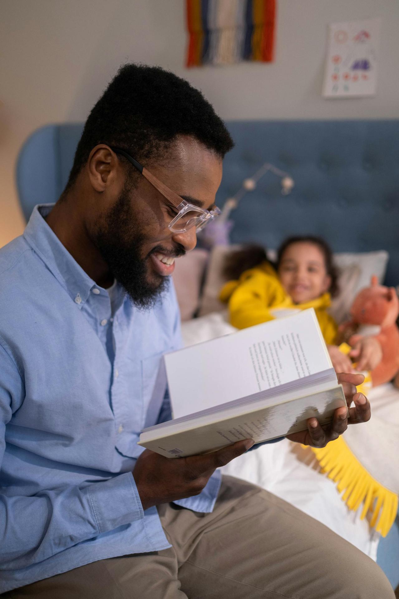 Smiling father reading a bedtime story to his daughter, enjoying a cozy night indoors.