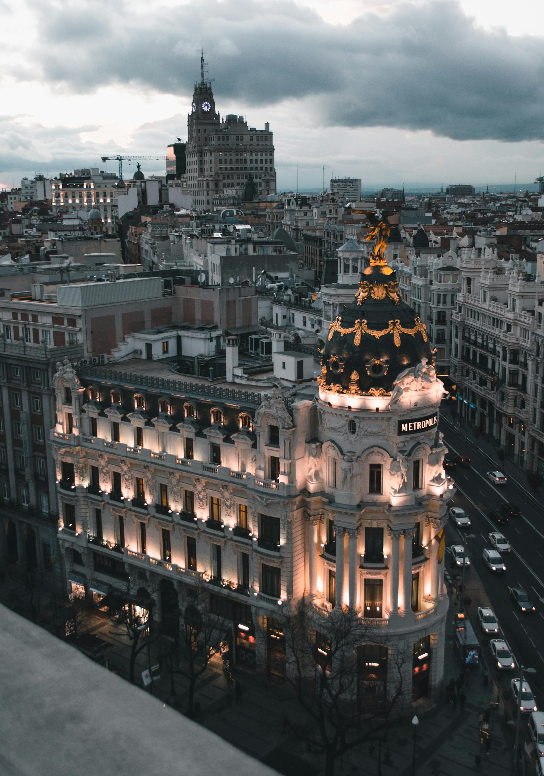 Aerial view of Madrid's Metropolis Building illuminated at dusk, showcasing urban architecture.