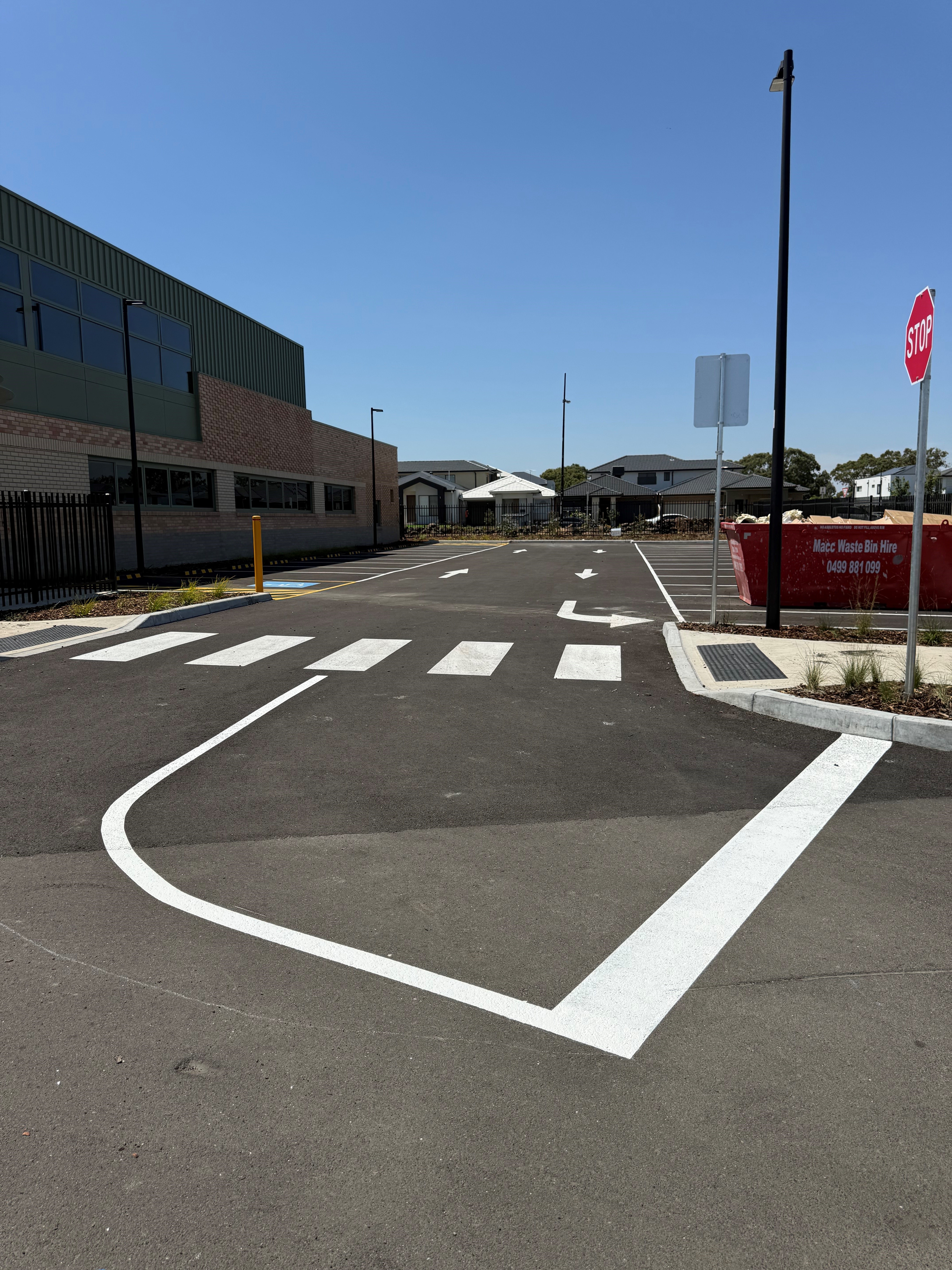 Completed commercial car park with fresh line marking, wheel stops and safety bollards