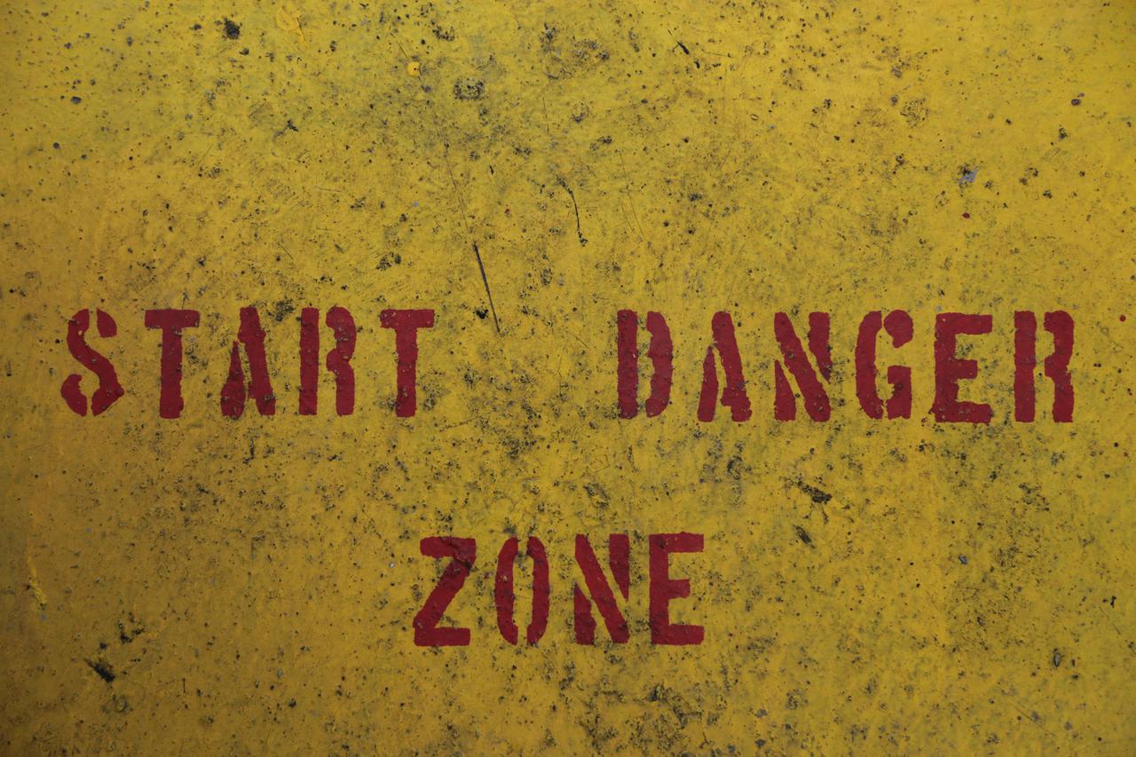Warning text on a Container Vessel This image captures the essence of caution with 'START DANGER ZONE' boldly painted in red on a textured yellow surface. The gritty, worn look adds a sense of urgency and the necessity for awareness. It’s an illustrative example of industrial safety signage and its importance in hazardous environments.