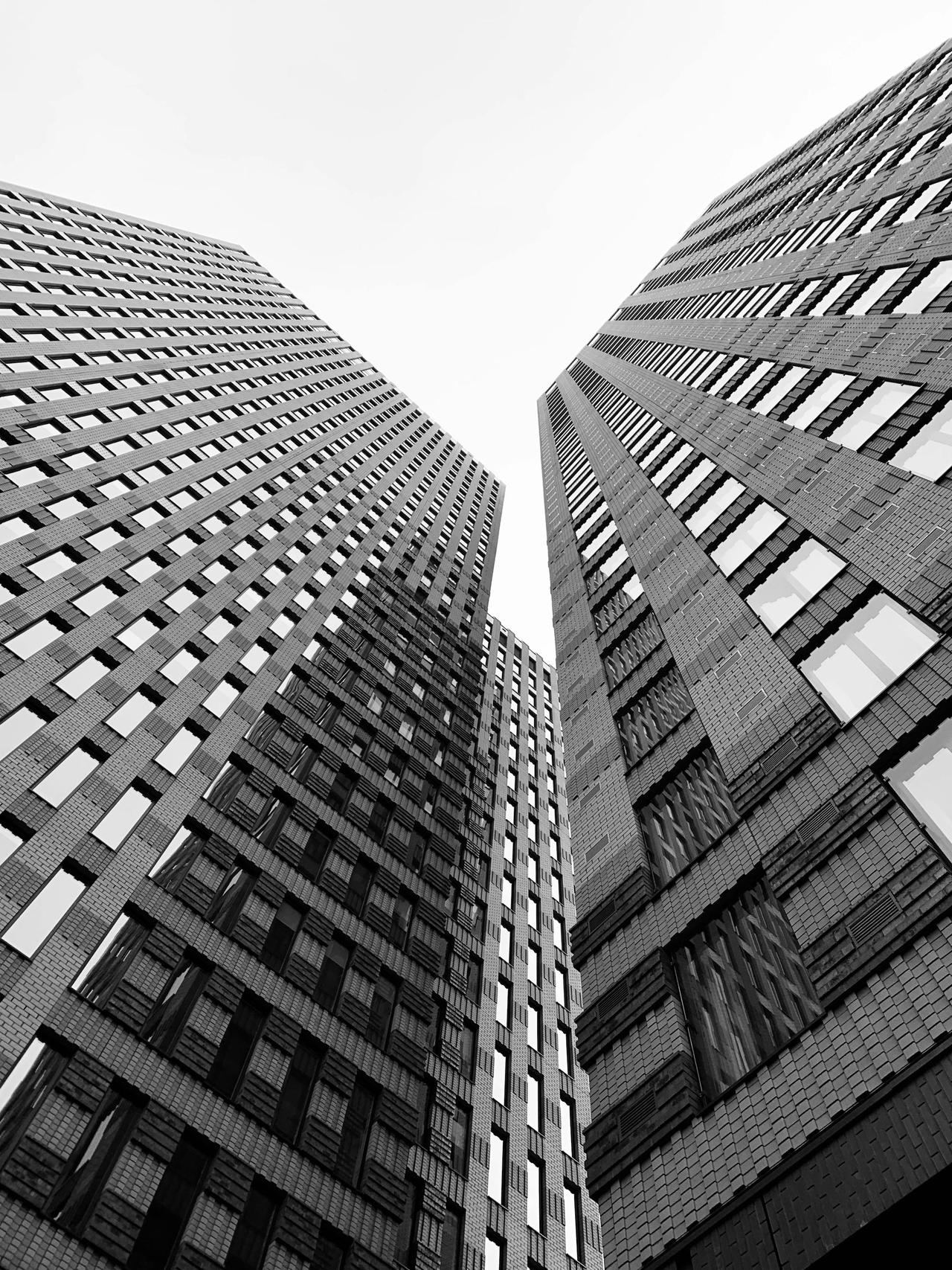 Dramatic black and white perspective of Amsterdam skyscrapers reaching towards the sky.
