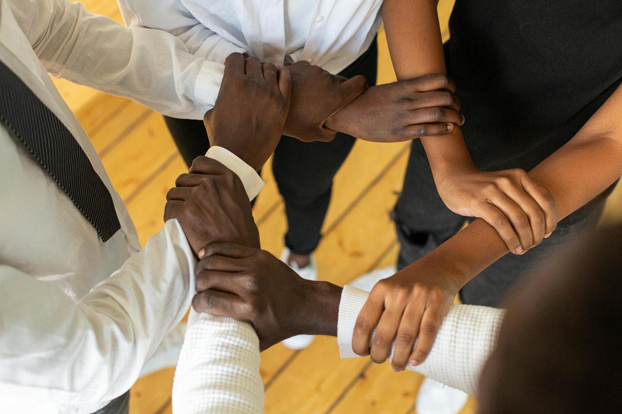Close-up of diverse hands in a circle, symbolizing teamwork and unity.