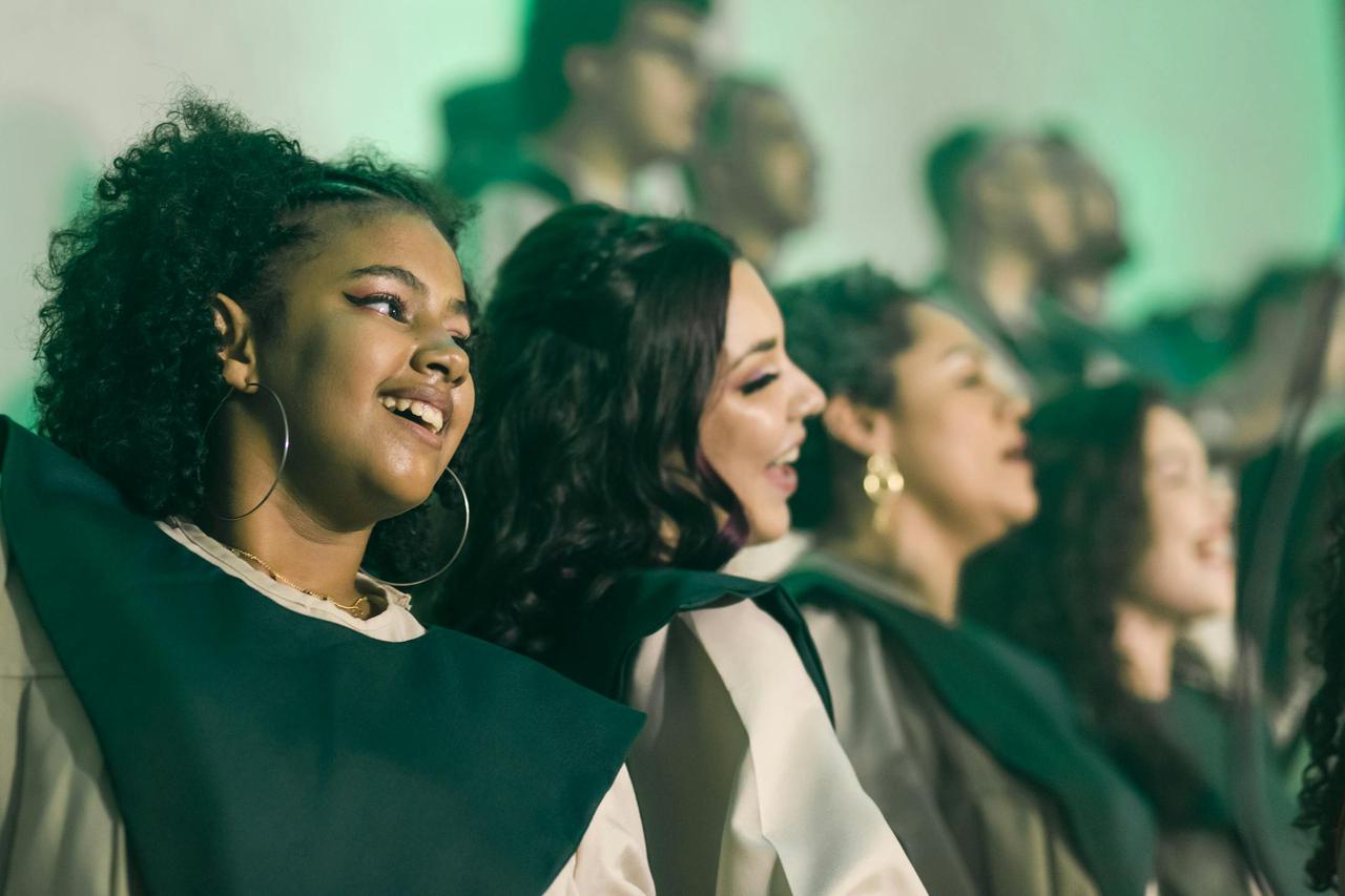 A lively choir performance with diverse women joyfully singing together in harmony.