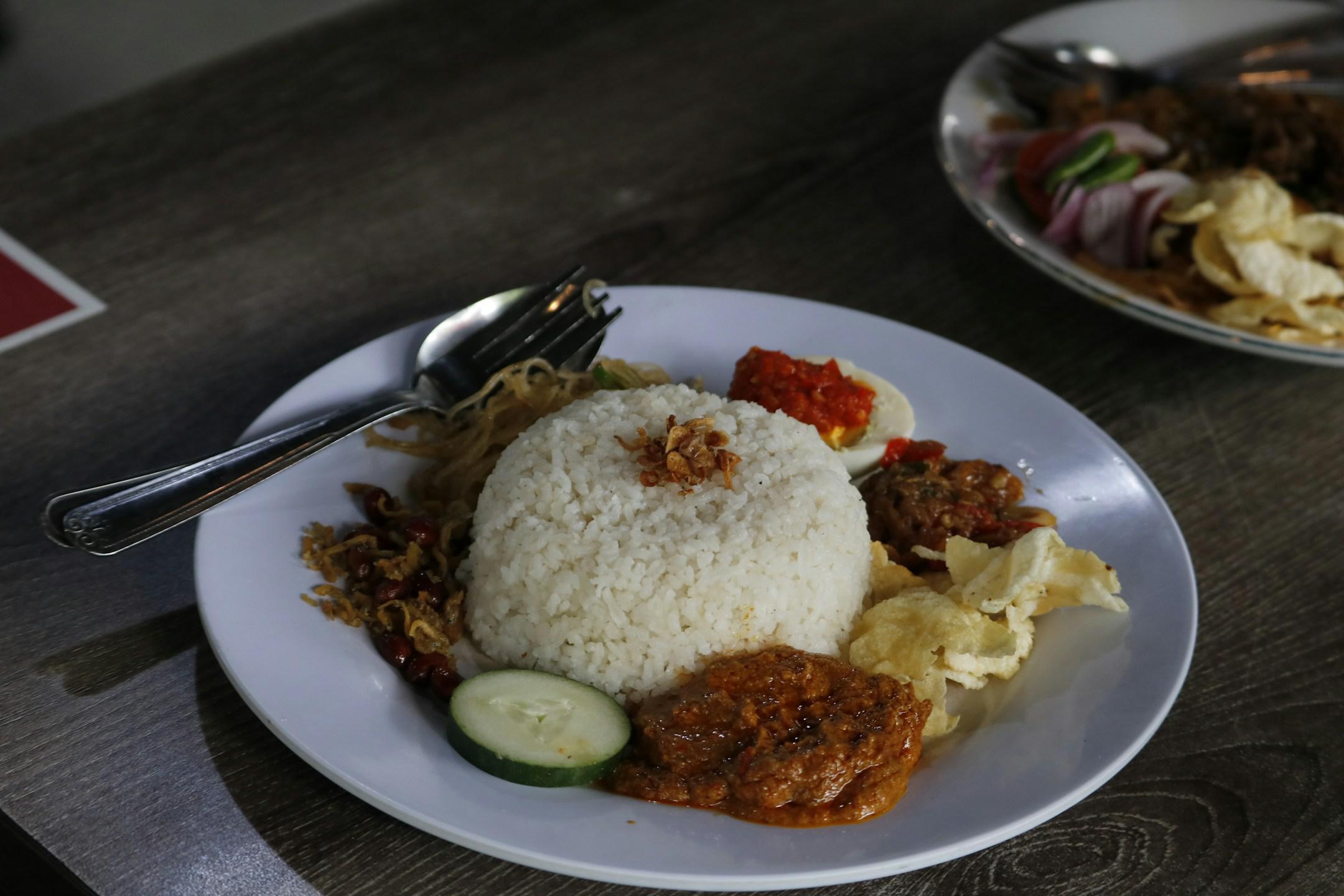 Nasi lemak, a traditional Malay curry paste rice dish served on a white plate.