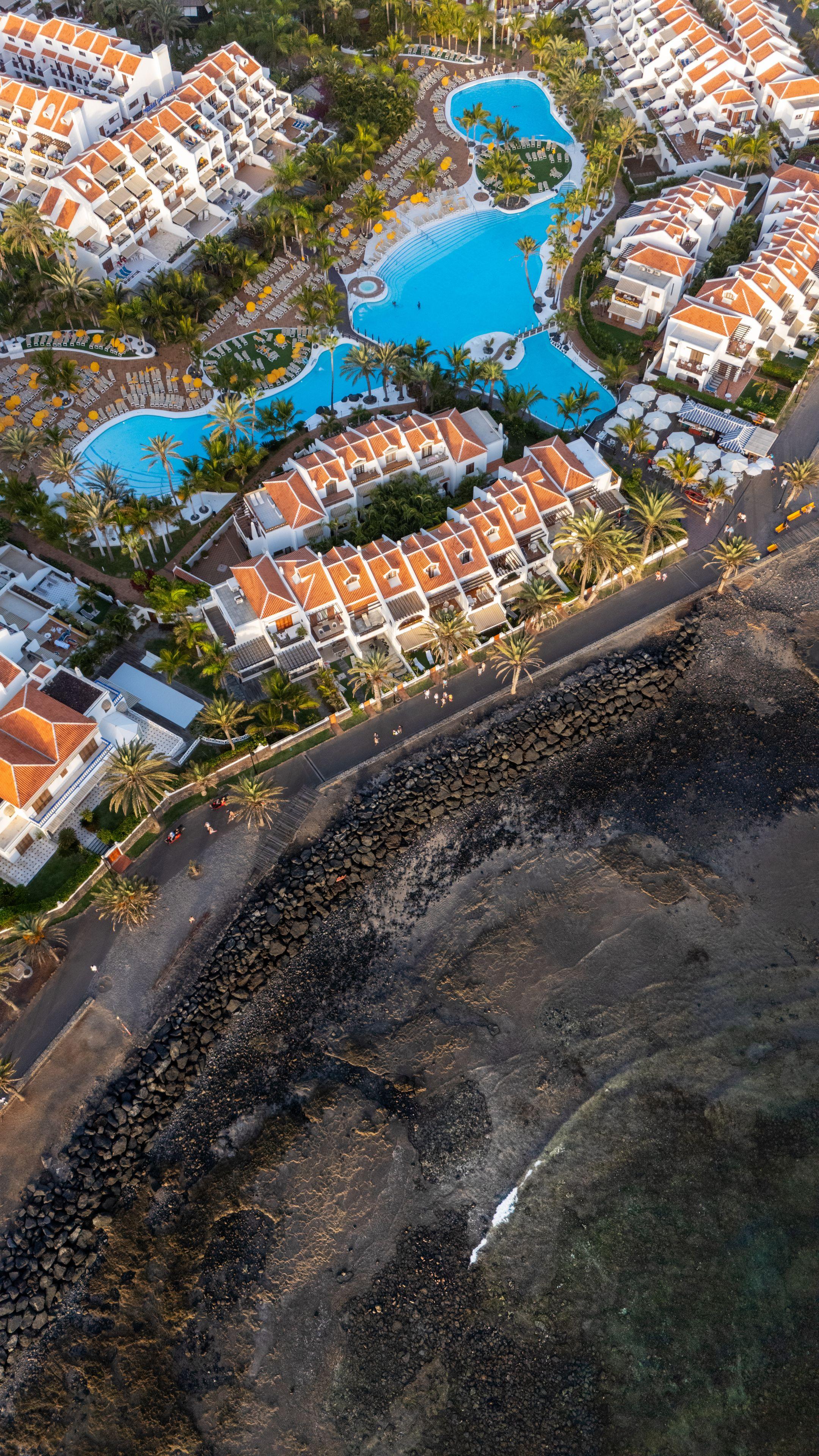 Stunning aerial shot of a seaside resort with pools and villas on the Canary Islands coastline.