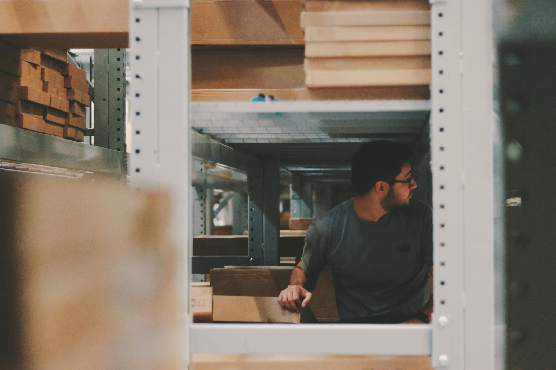 Man organizing wooden planks on warehousing shelves, creating an efficient storage solution.