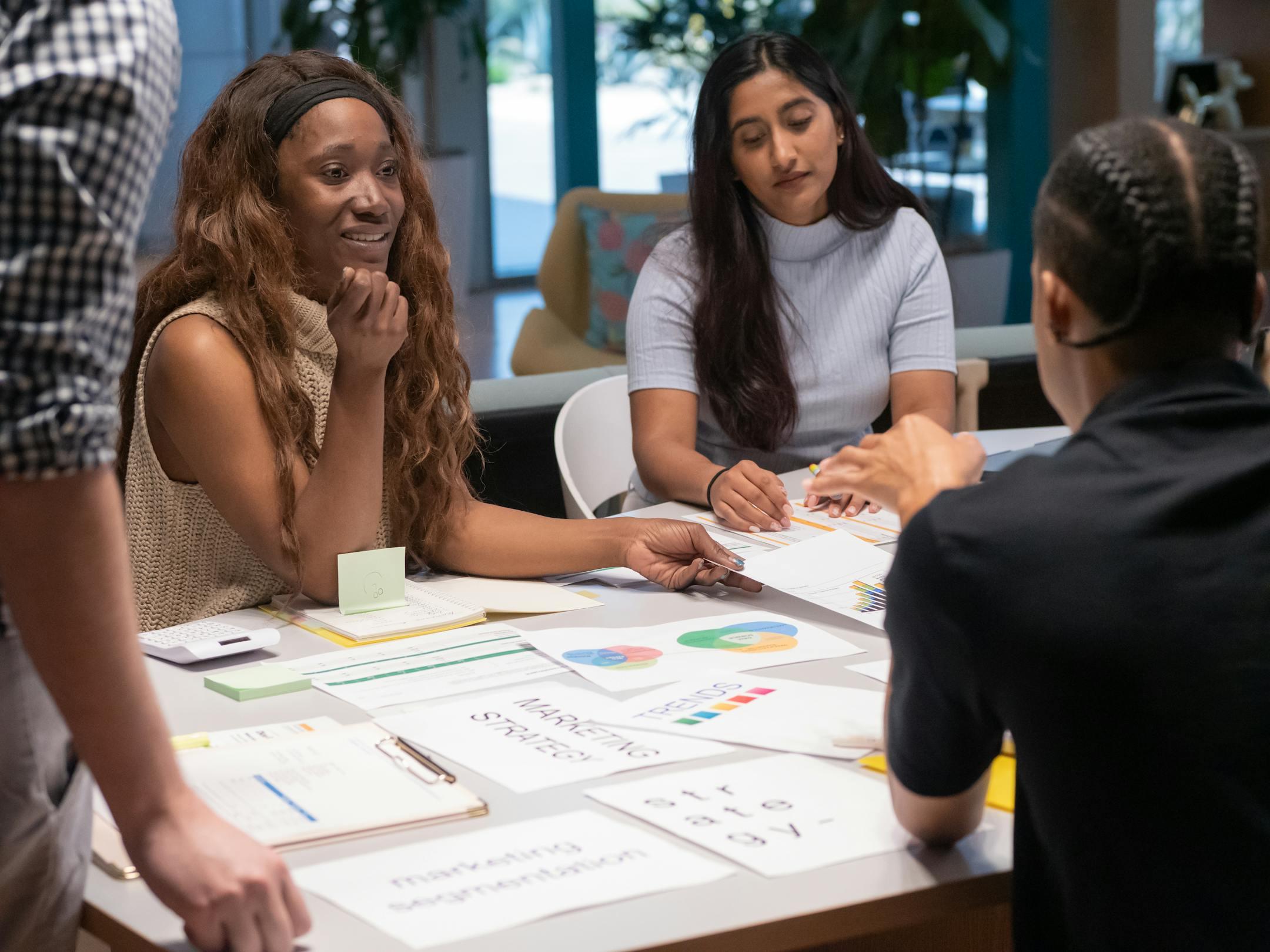 Group of coworkers discussing marketing strategies around a table in a contemporary workspace.