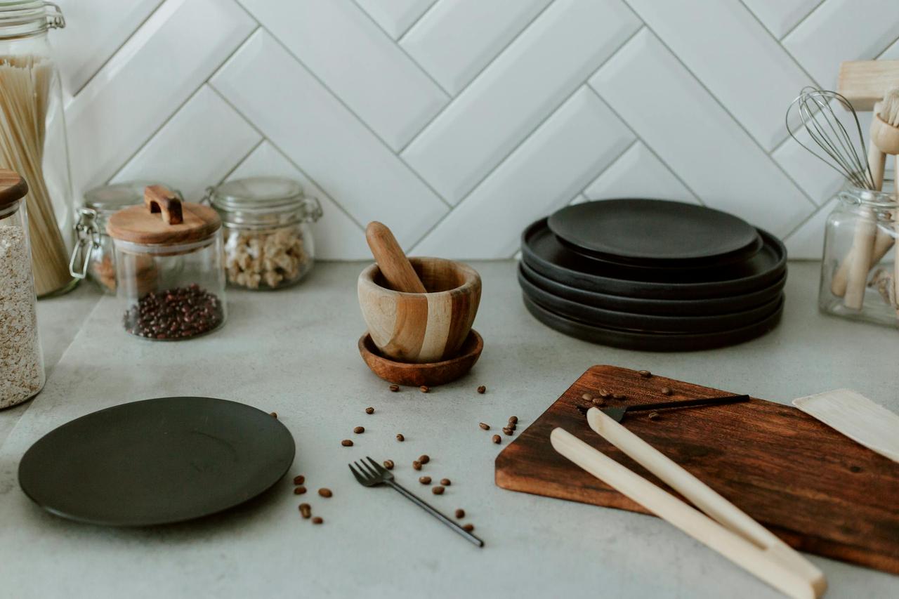 A modern kitchen with black plates, jars, and kitchen tools on a countertop.