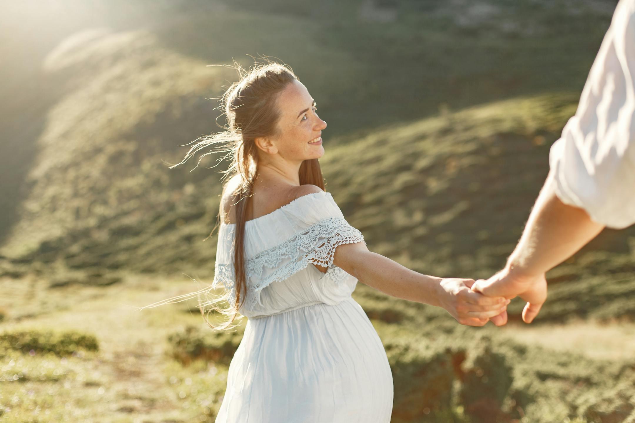 Happy couple walking hand-in-hand in a sunlit meadow, enjoying nature.
