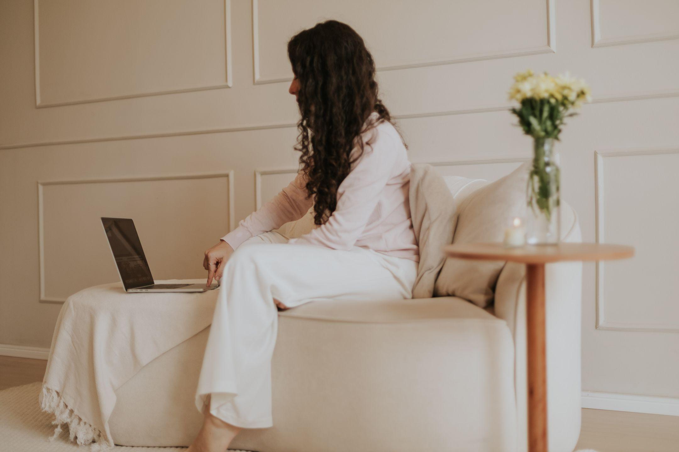Woman working on a laptop in a minimalist home office with soft neutral tones and a peaceful ambiance.