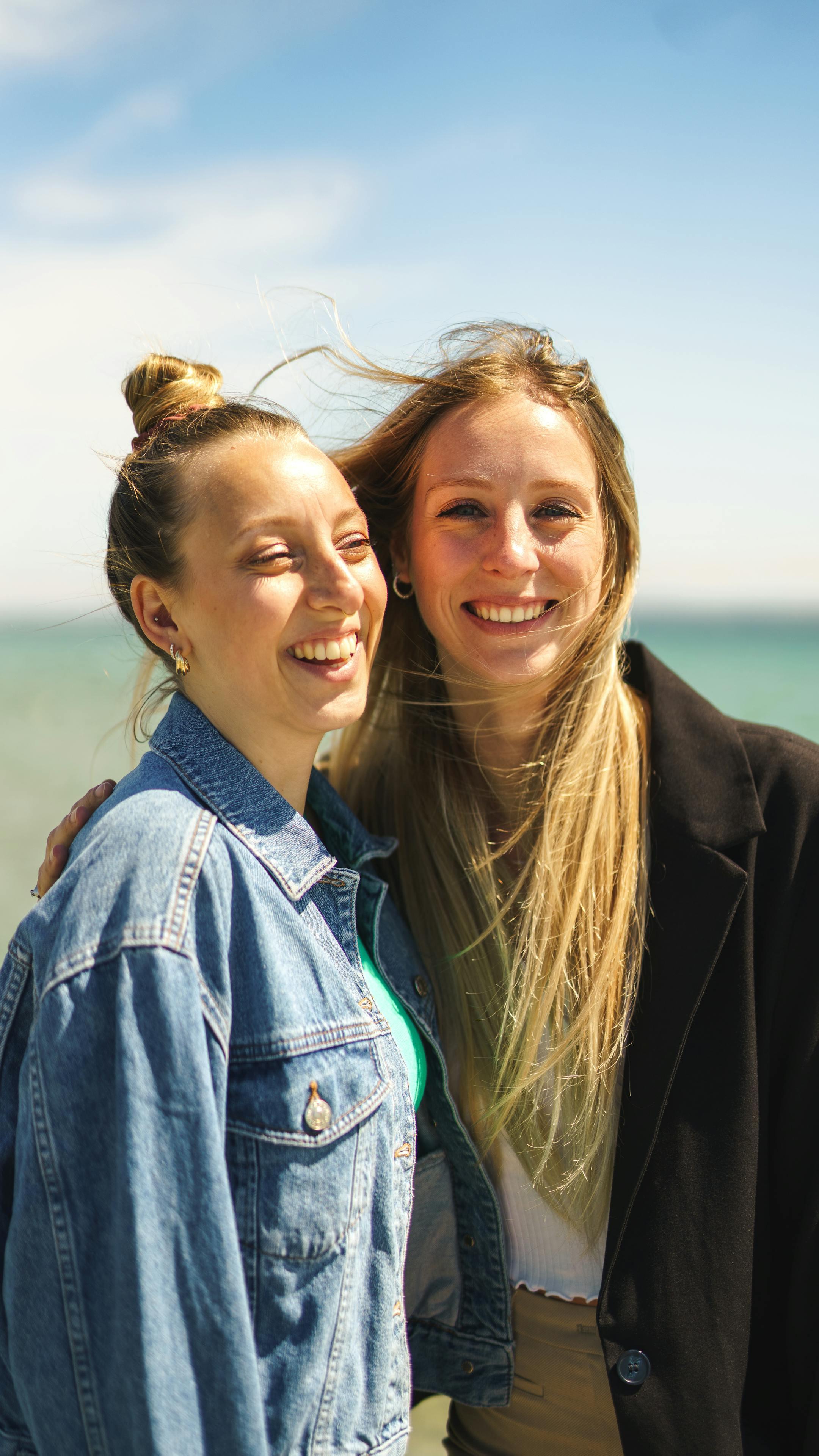 Two young women enjoying a sunny day at the beach, smiling and carefree.