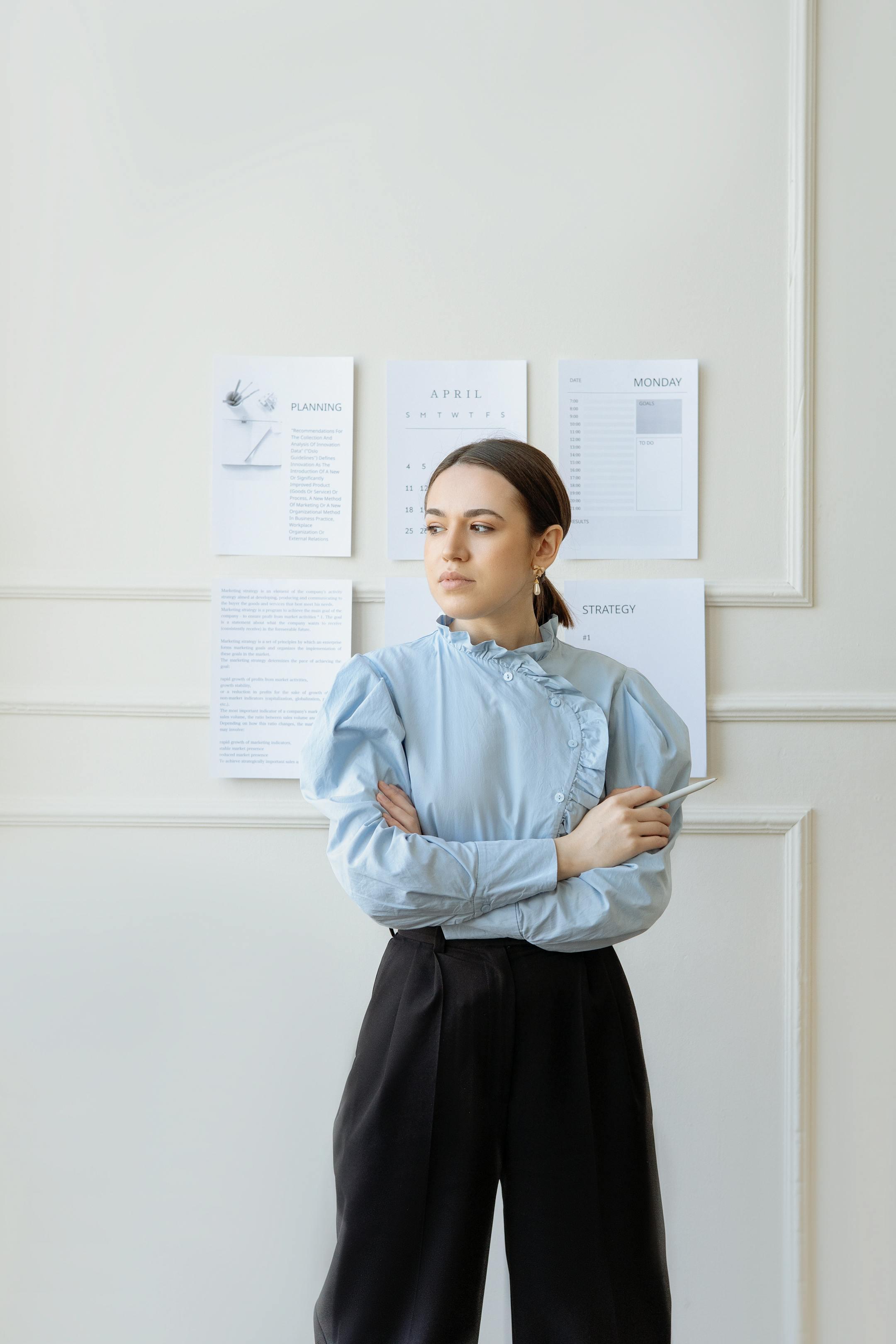 A woman standing with arms crossed, exuding confidence in an office setting.