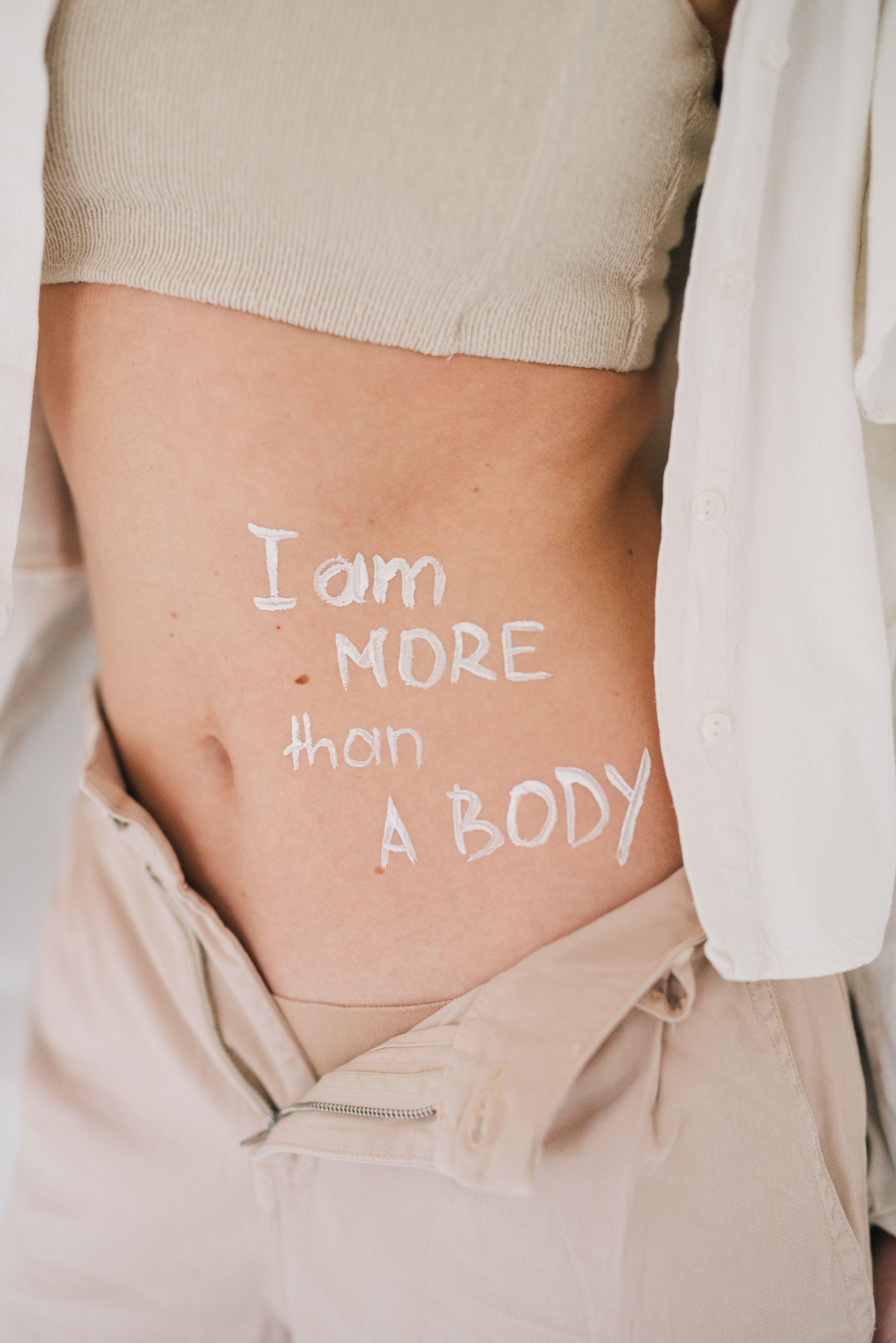 Close-up of a woman's torso with empowering text promoting body positivity.