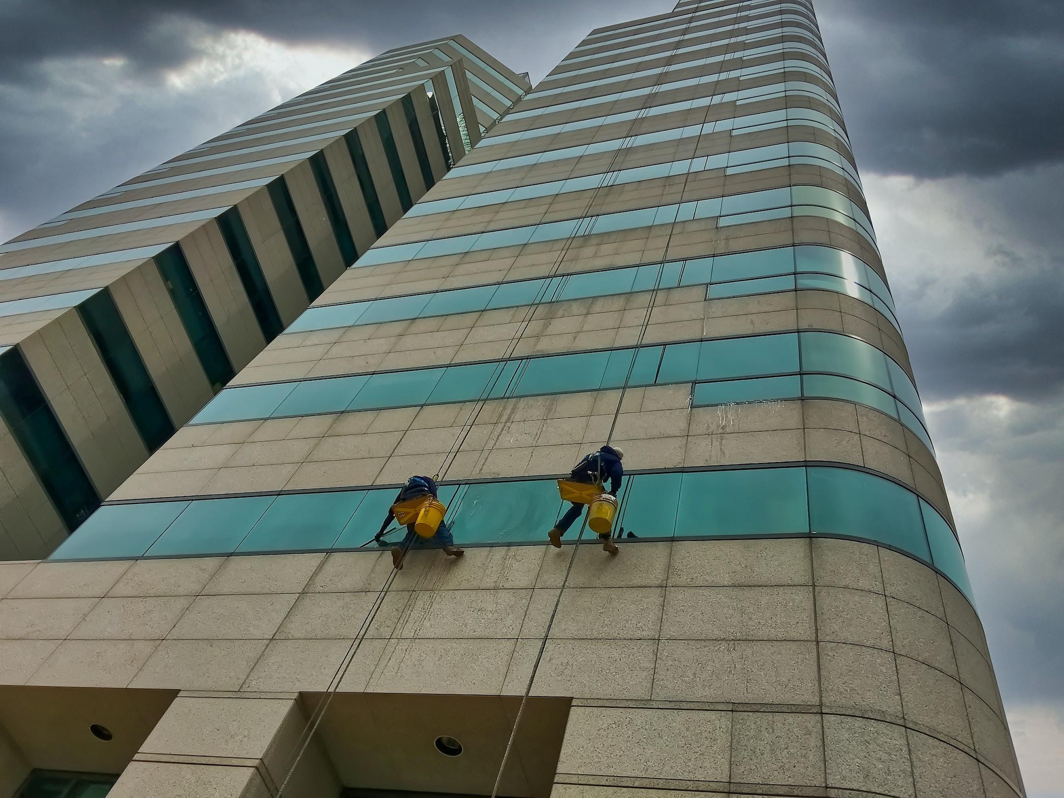 Image of two window washers on a skyscraper, a good example of people who will probably need a workers compensation lawyer.