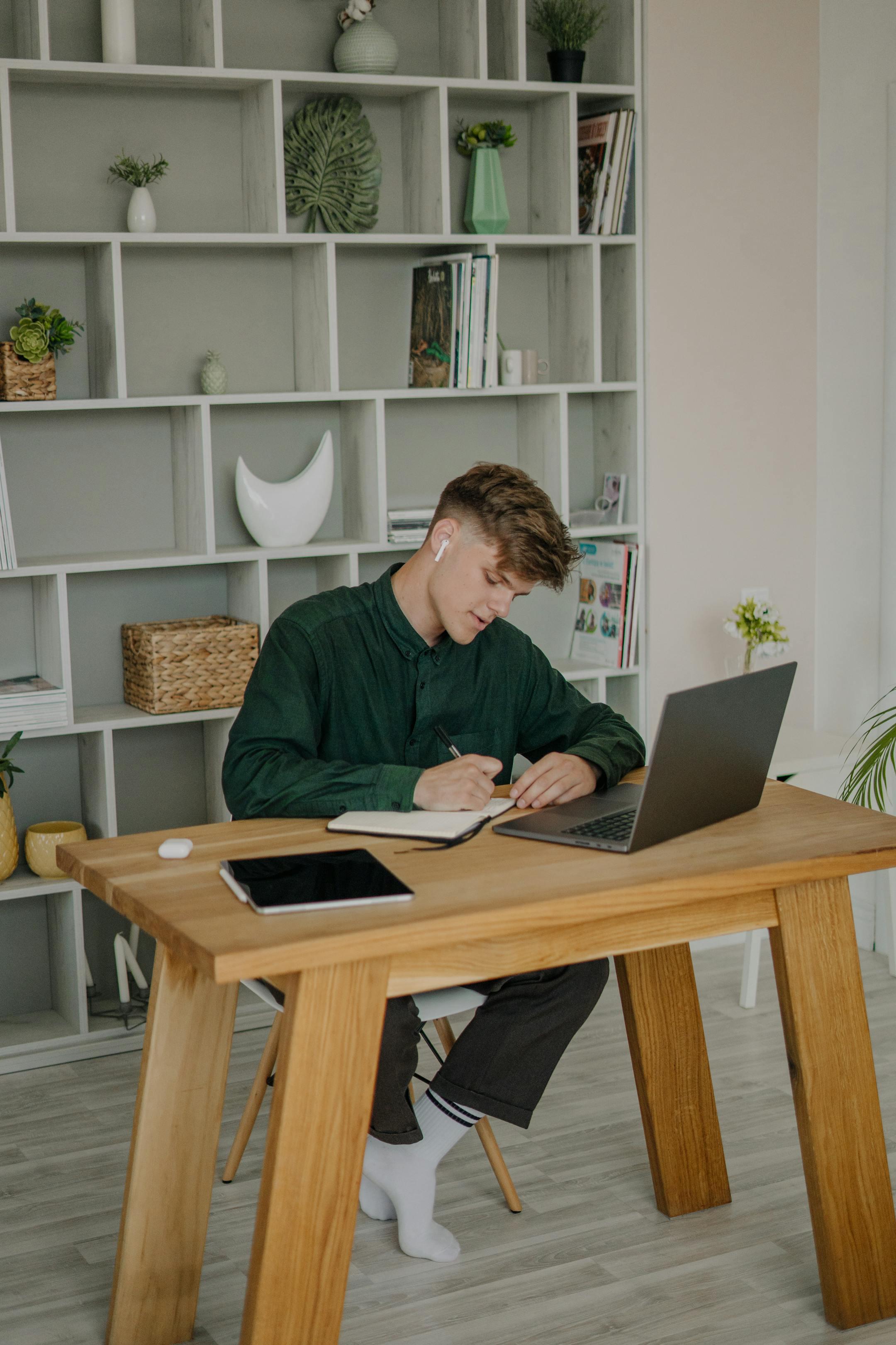 Adult male with earphones working at a laptop in a modern indoor setting.