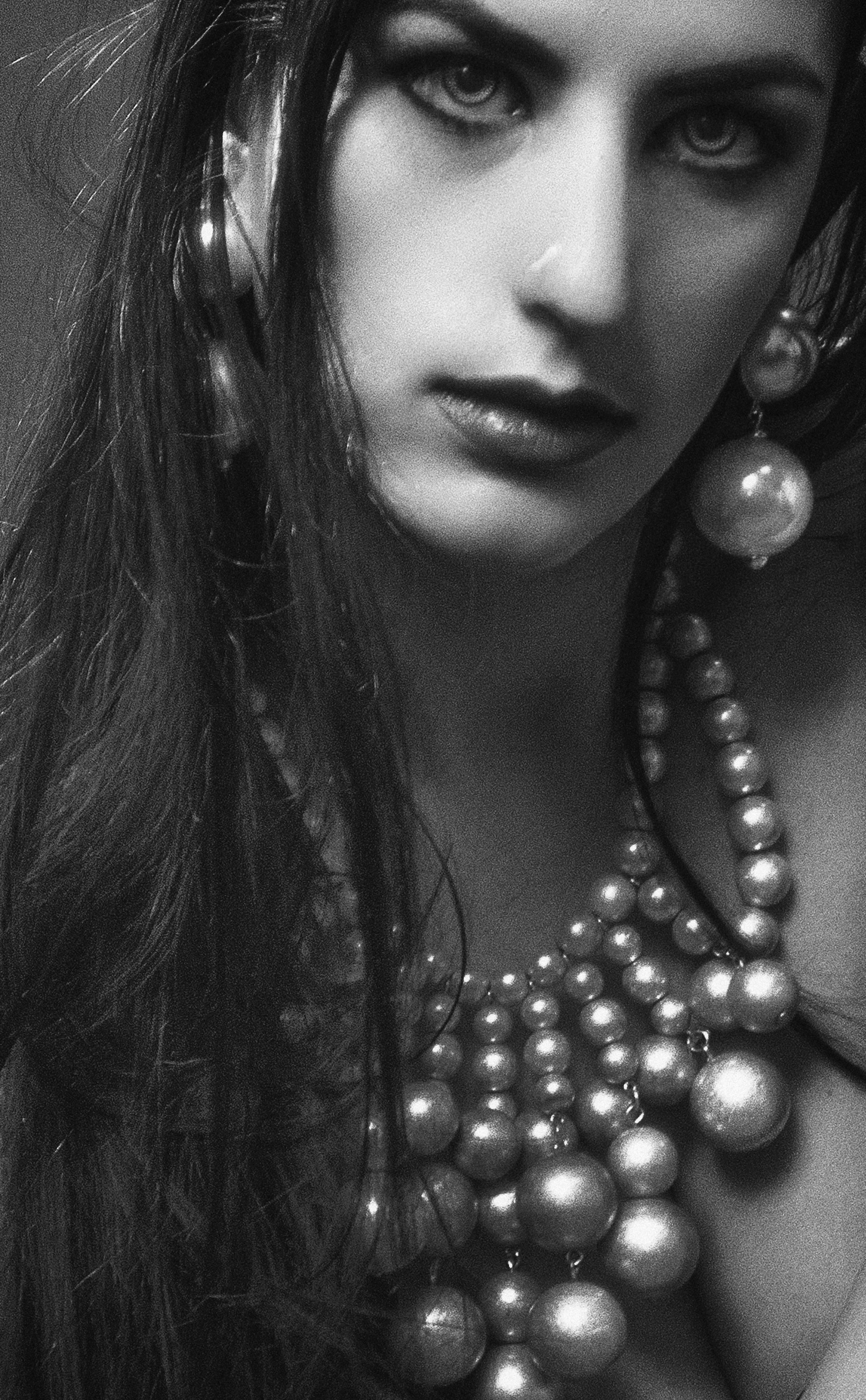 Black and white portrait of a woman wearing elegant pearl jewelry.