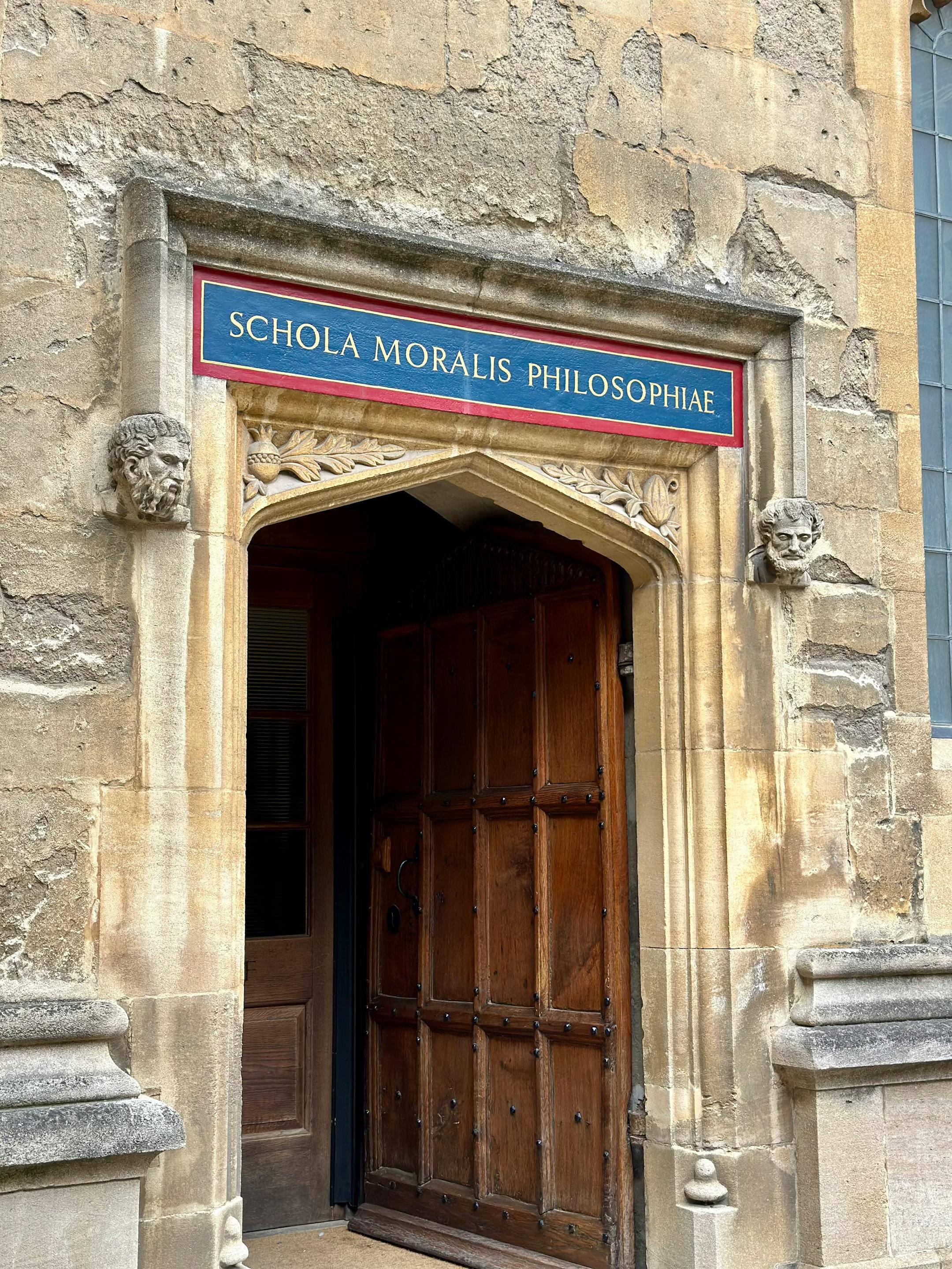 Historic entrance of Schola Moralis Philosophiae in Oxford with detailed stonework.