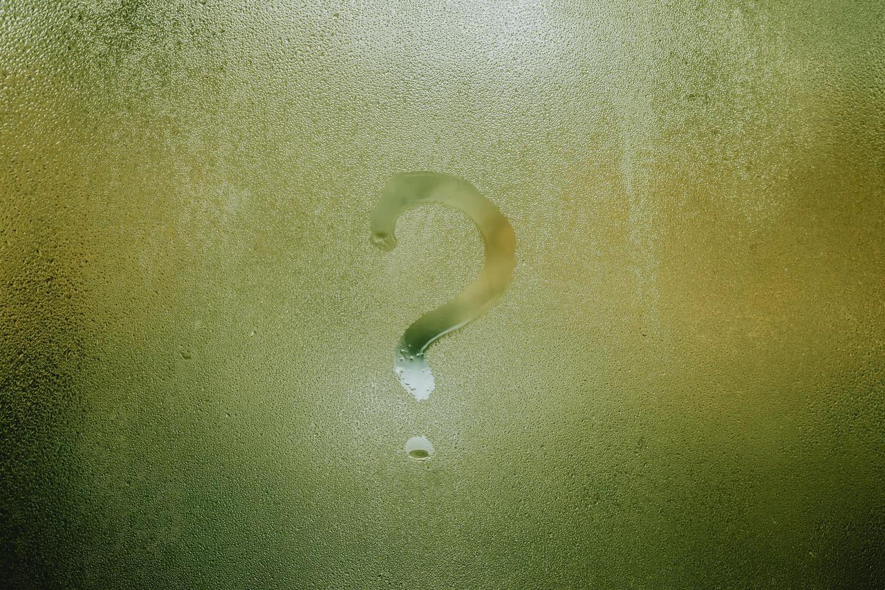 A question mark drawn on foggy glass, evoking curiosity and mystery.