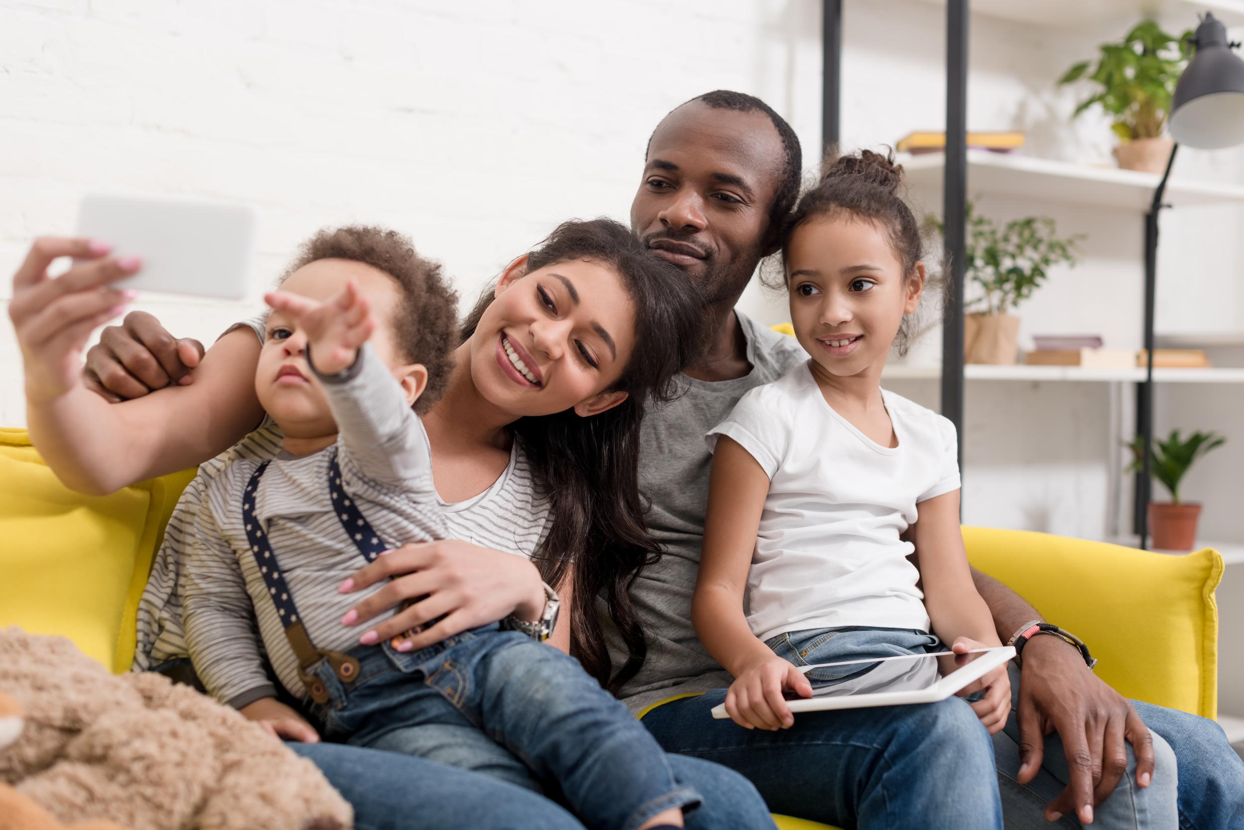 happy-young-family-taking-selfie-on-couch-at-livin-2024-11-19-05-10-09-utc.jpg