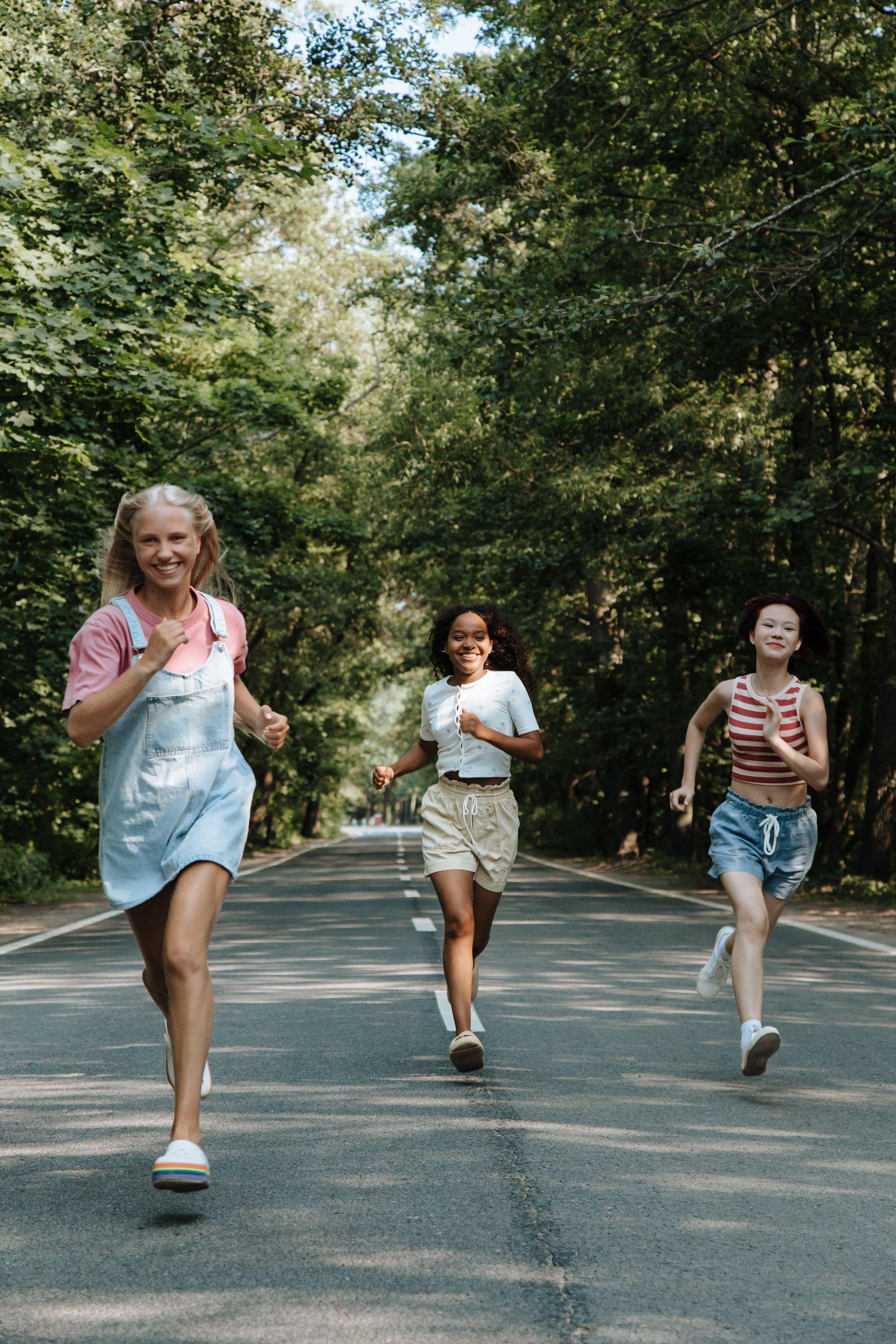 Three teenagers enjoying a run on a scenic forest road on a sunny summer day.
