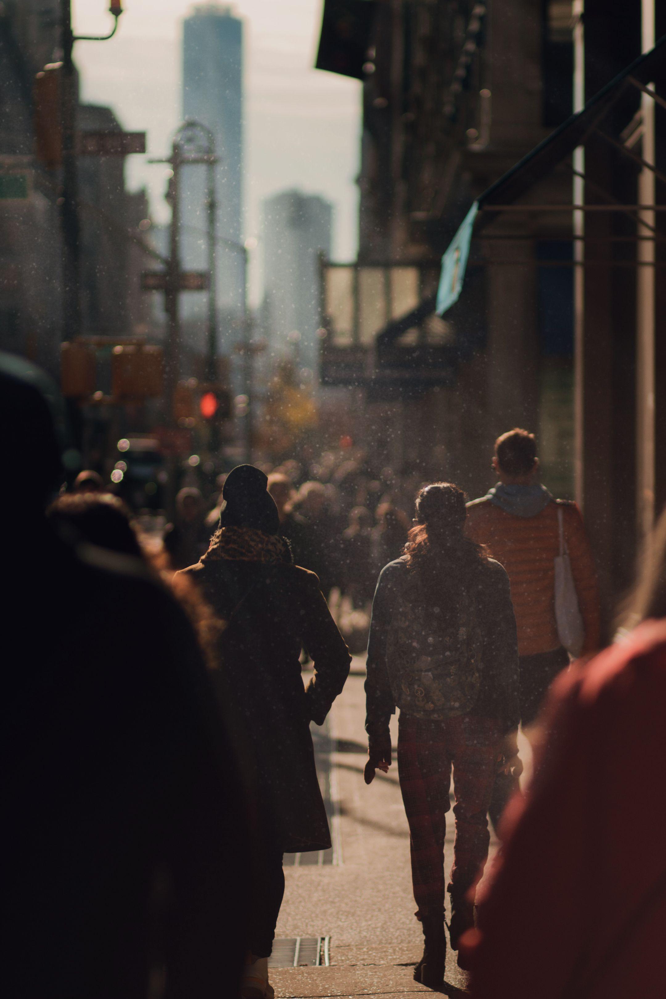A bustling city street filled with people walking during sunset, capturing urban life.