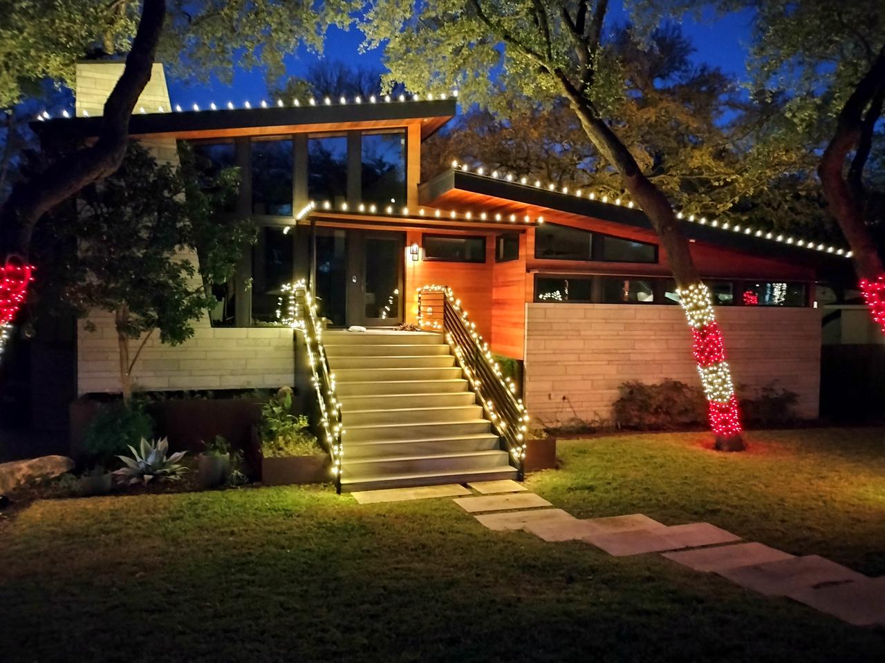 Southwest adobe-style home with warm white twinkle lights and red garland