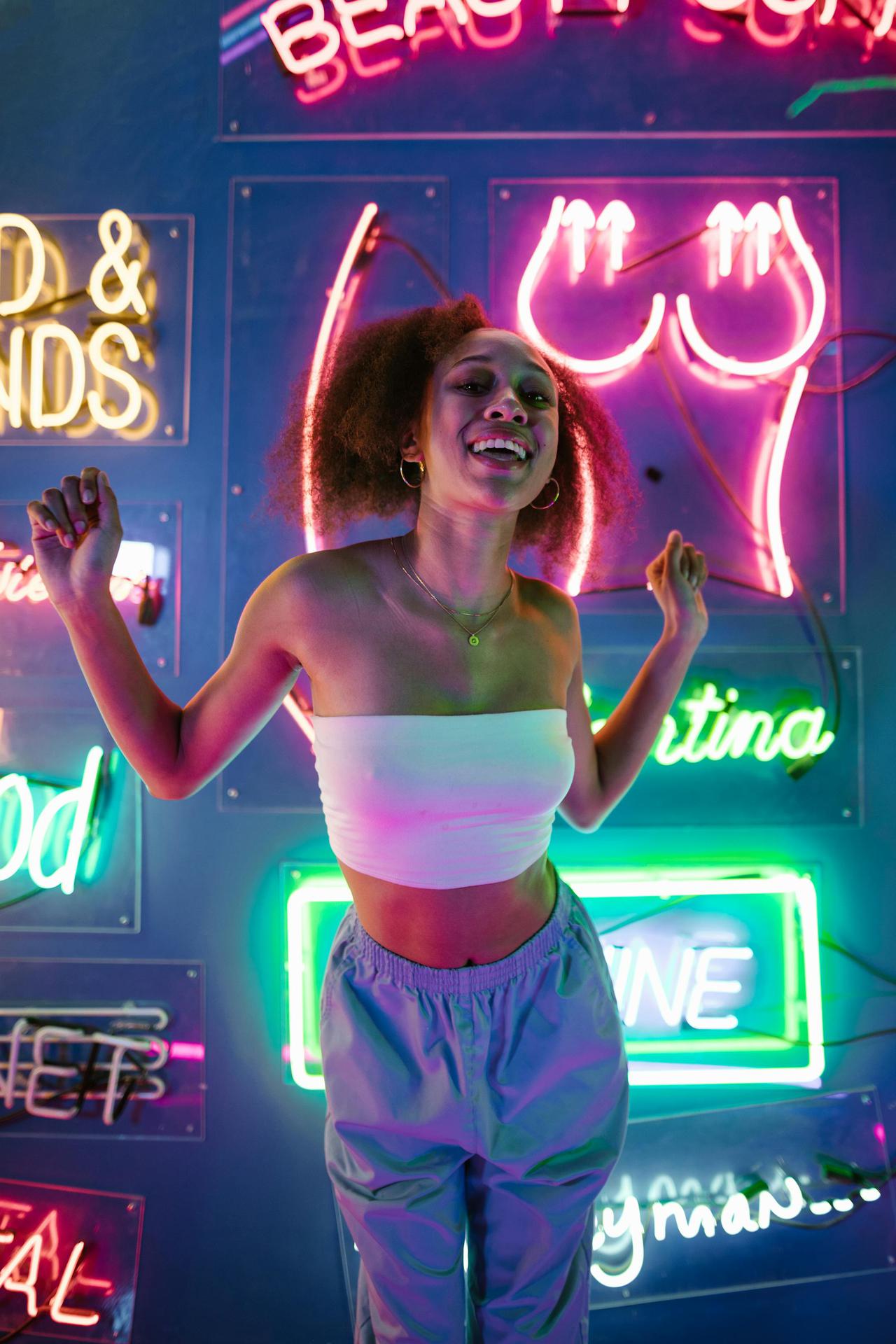 A young woman enjoying nightlife surrounded by colorful neon lights in a club setting.