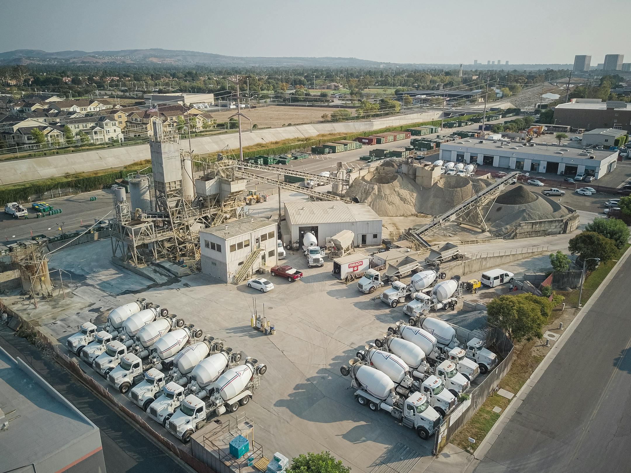 Aerial shot of a bustling cement manufacturing plant with mixer trucks and industrial equipment.