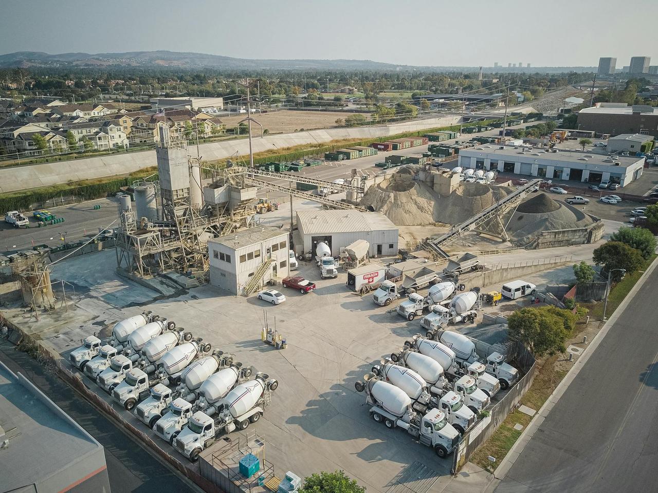 Aerial shot of a bustling cement manufacturing plant with mixer trucks and industrial equipment.