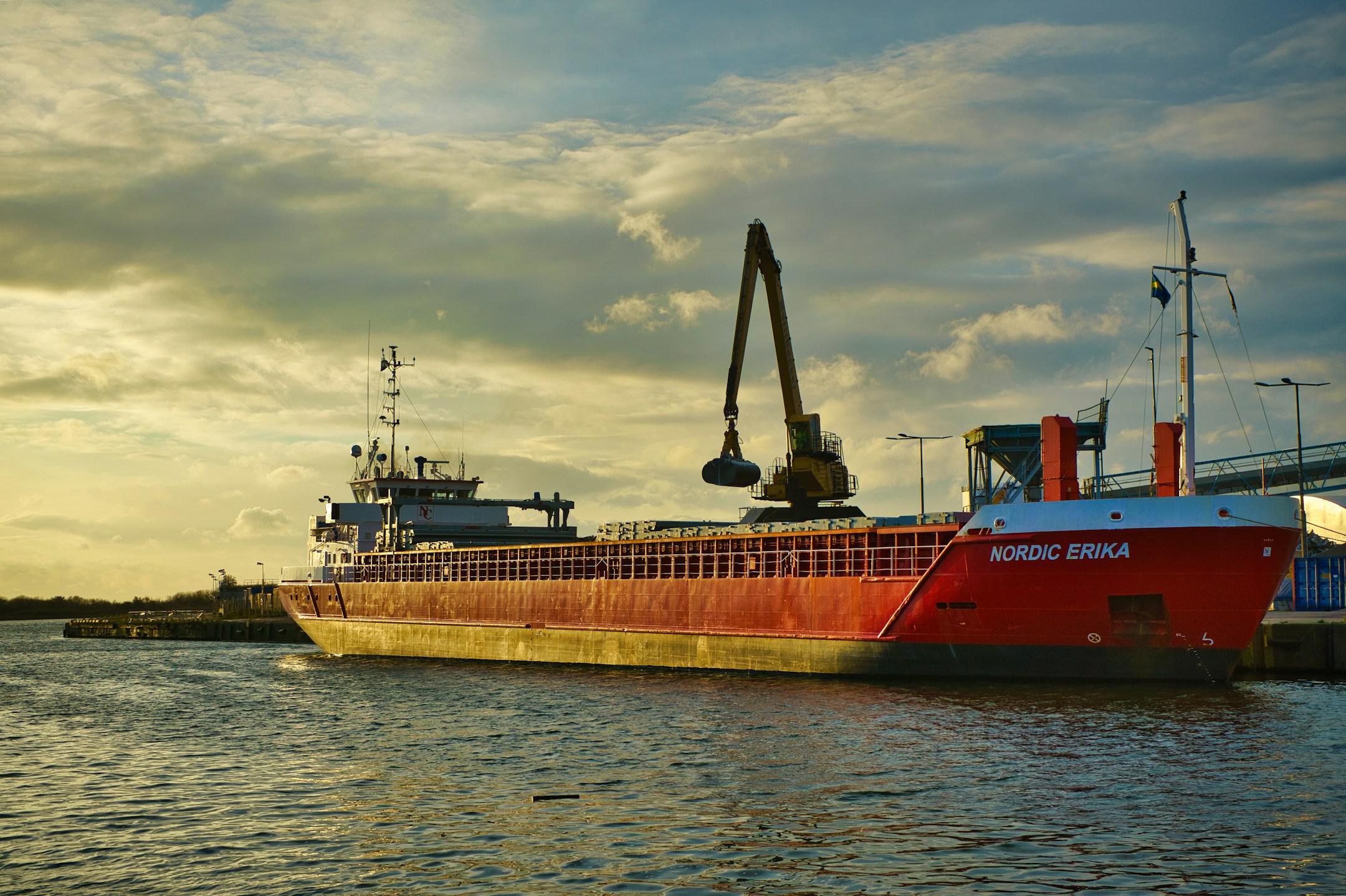 Bulk Carrier at Commercial Dock on the Harbor with Cloudy Sky and Dramatic Sunset