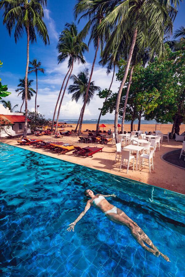 woman swimming floating in the pool in a tropical….jpg