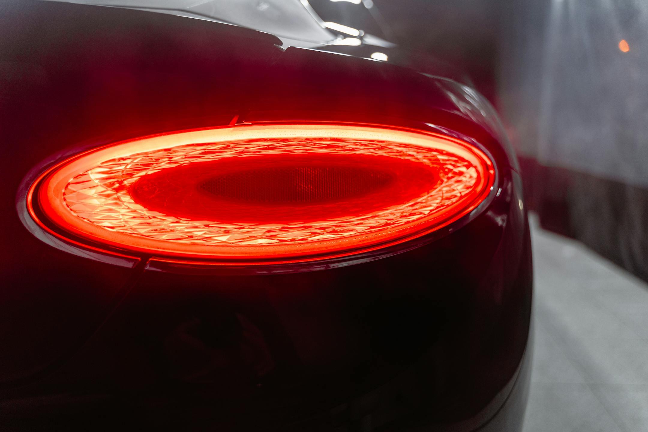 A detailed view of a car's red taillight illuminated at night.
