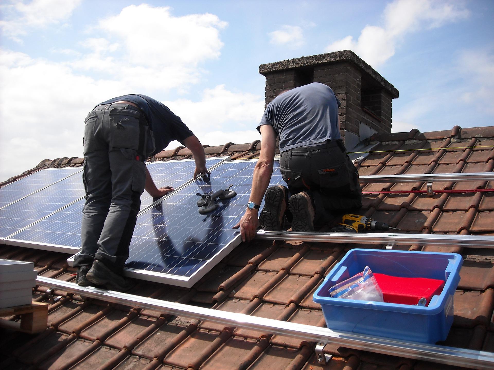 Two men installing solar panels on roof